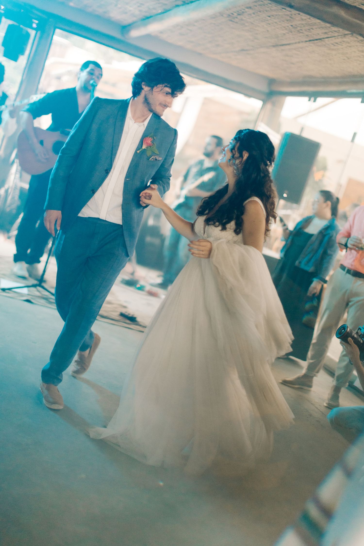 Dancers moving across a blue-tinted dance floor during a celebration.