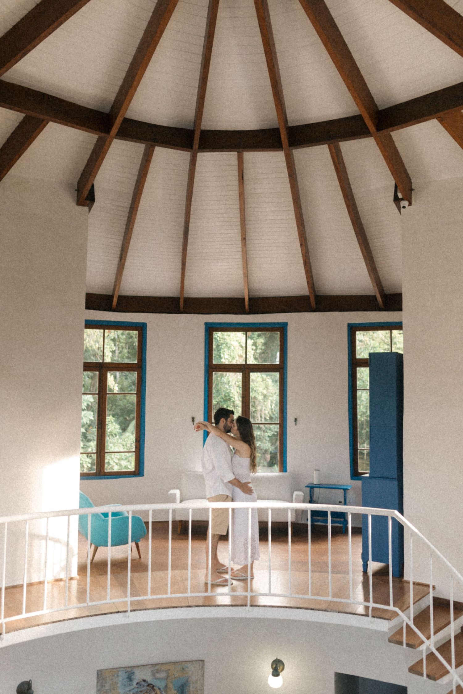 Interior of a round room with vaulted ceiling, white walls and blue window frames.