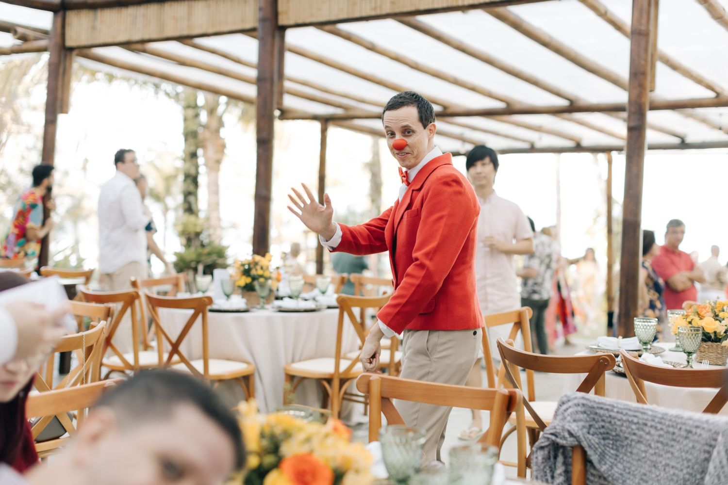 Wedding celebration in covered outdoor venue with person in bright red jacket among tables.