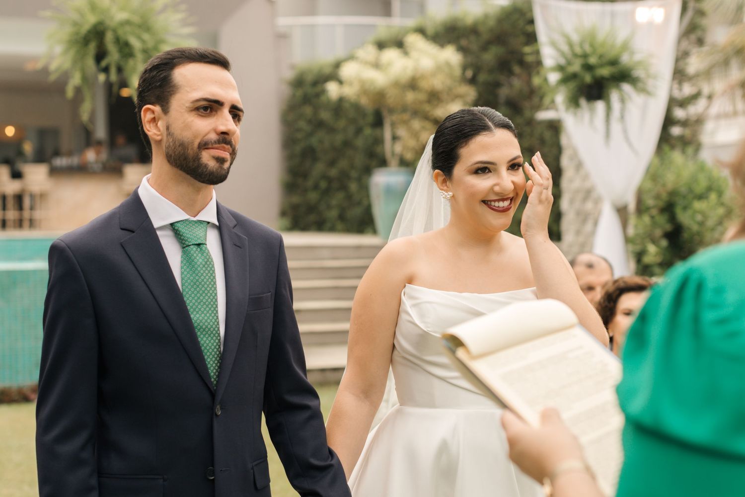 Elegant wedding party interacting outdoors with touches of emerald green and white decor.