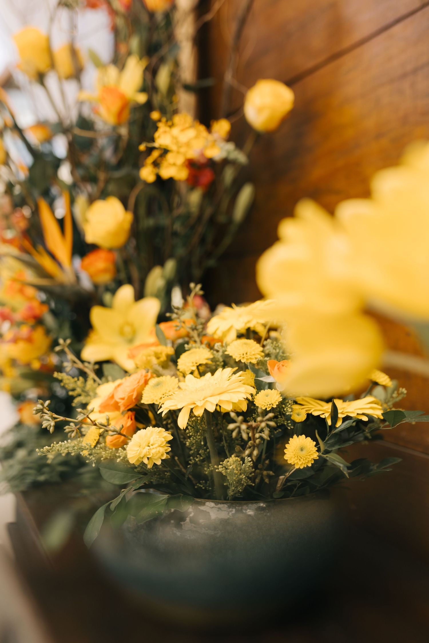 Vibrant yellow and orange floral centerpiece arrangement in soft focus.