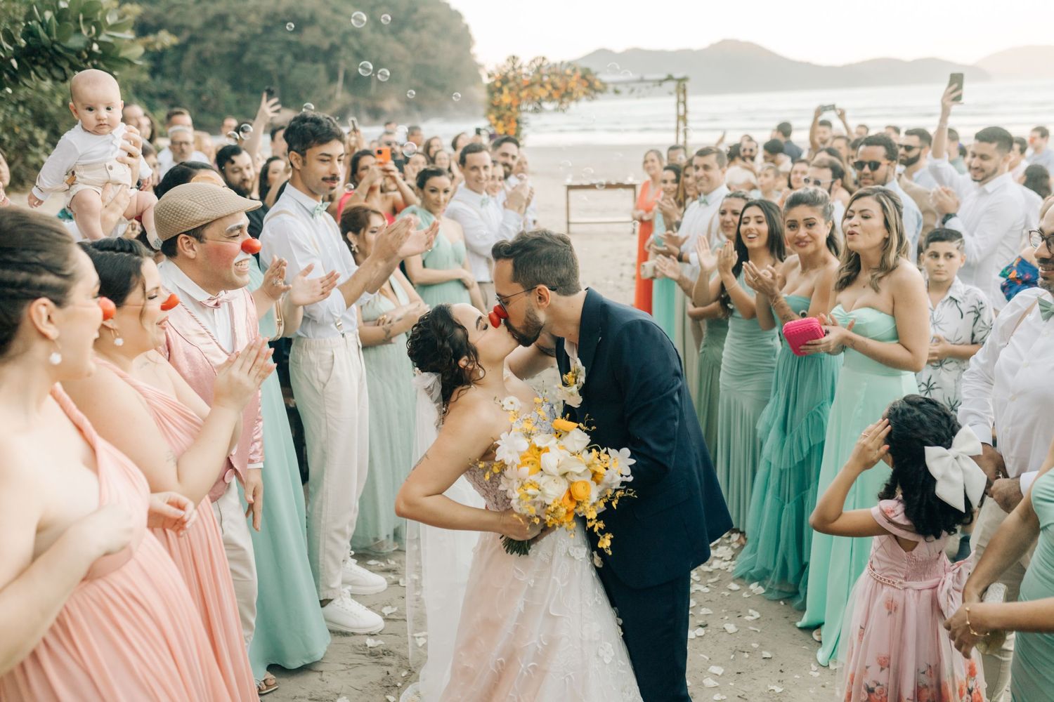 Wedding celebration on beach with bridal party in mint and coral colors.