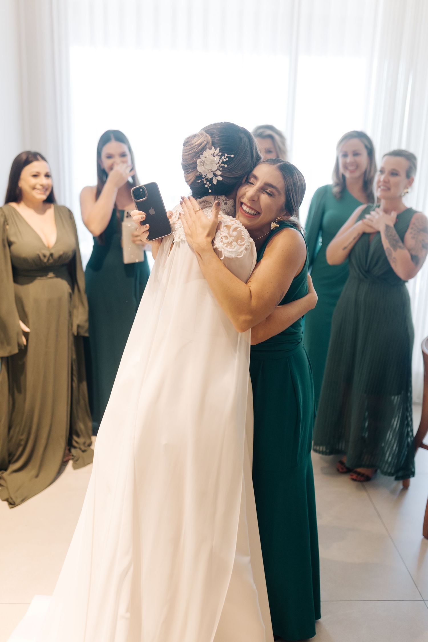 Emotional moment during wedding preparations with group in emerald green dresses.