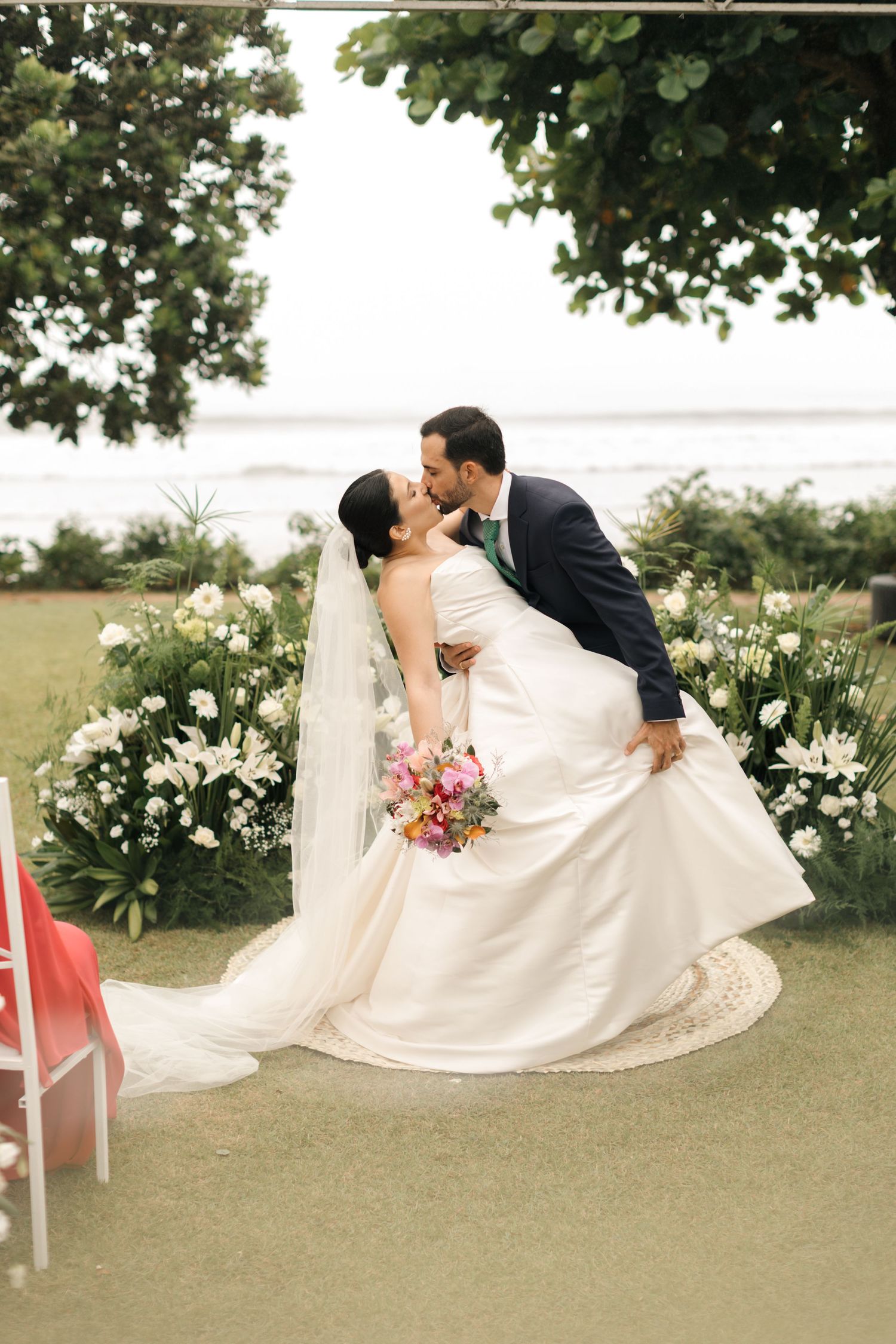 Wedding couple lying in grass with white dress spread out artistically.