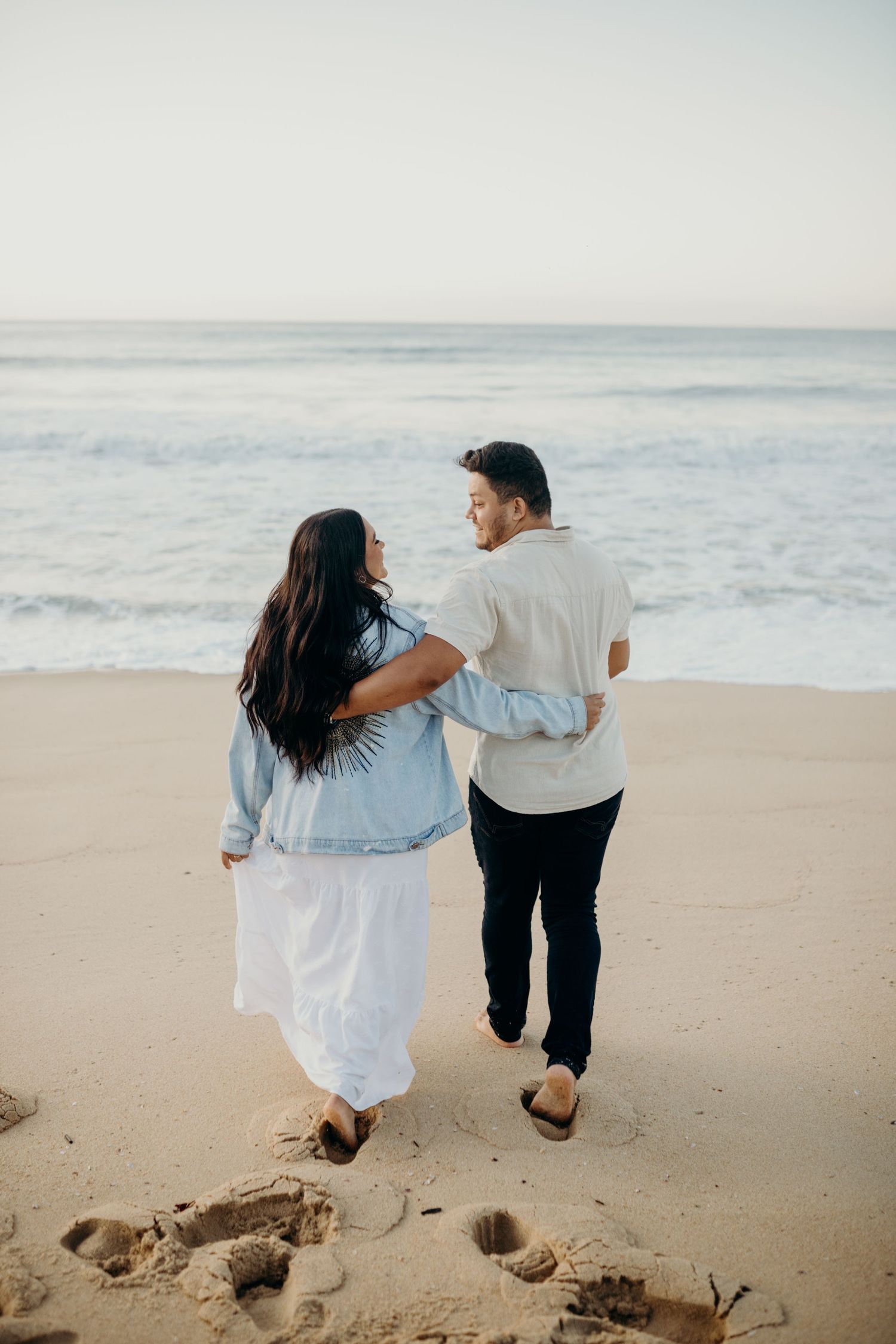 Couple enjoying a romantic moment on a sandy beach by the ocean.