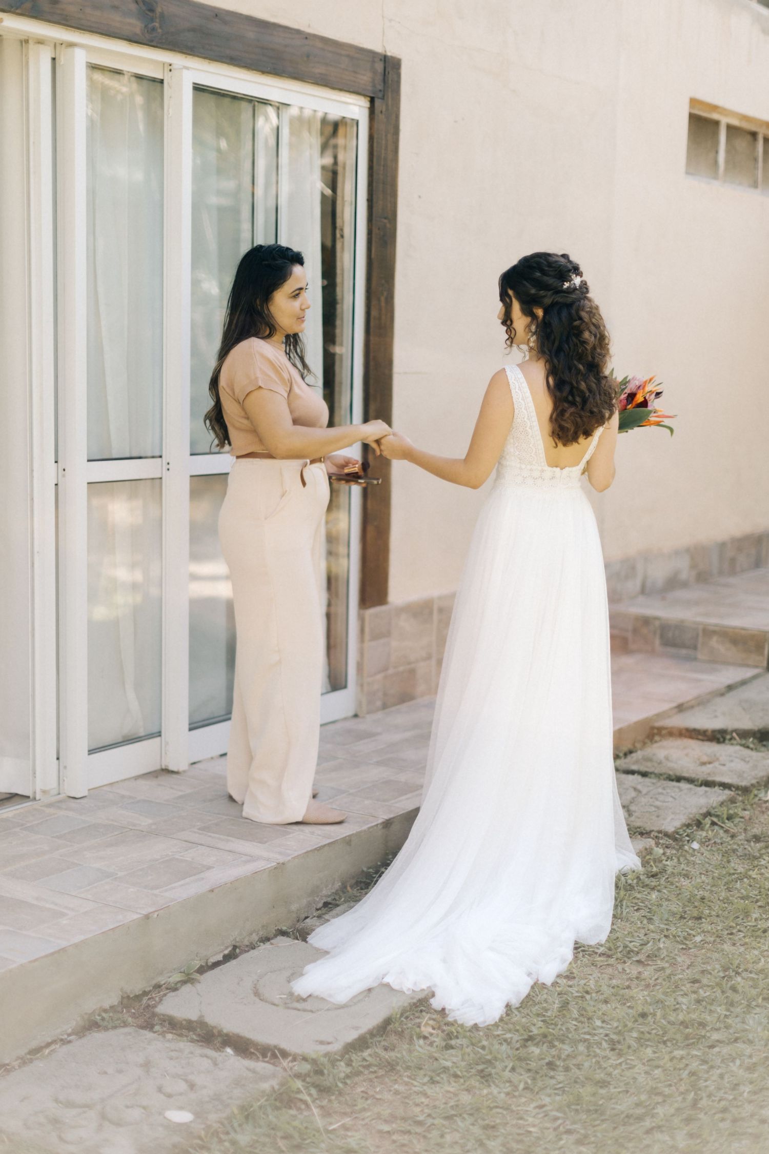 Candid moment between two people during wedding preparations outside.