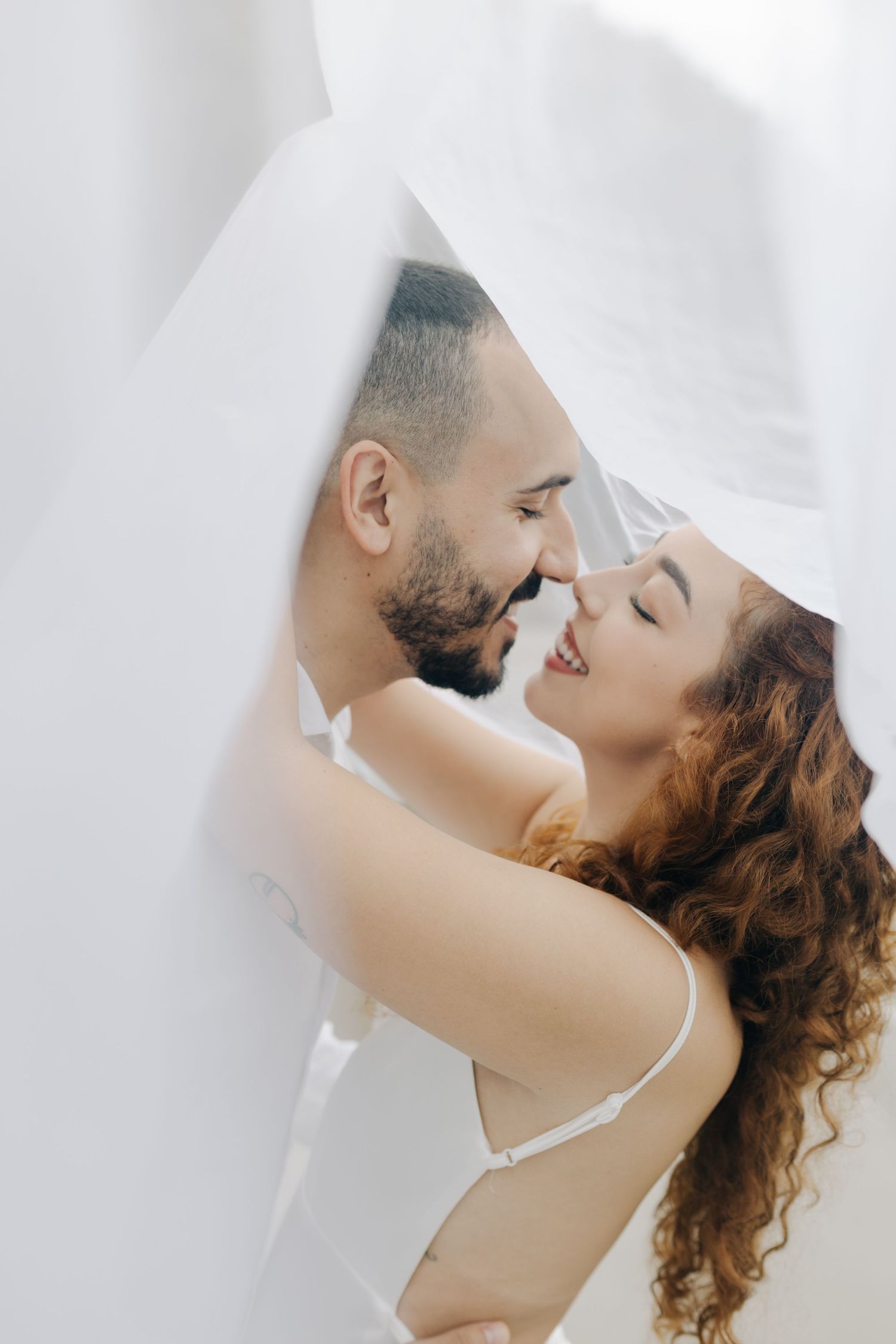 Close-up wedding photo of couple sharing intimate moment under sheer veil.
