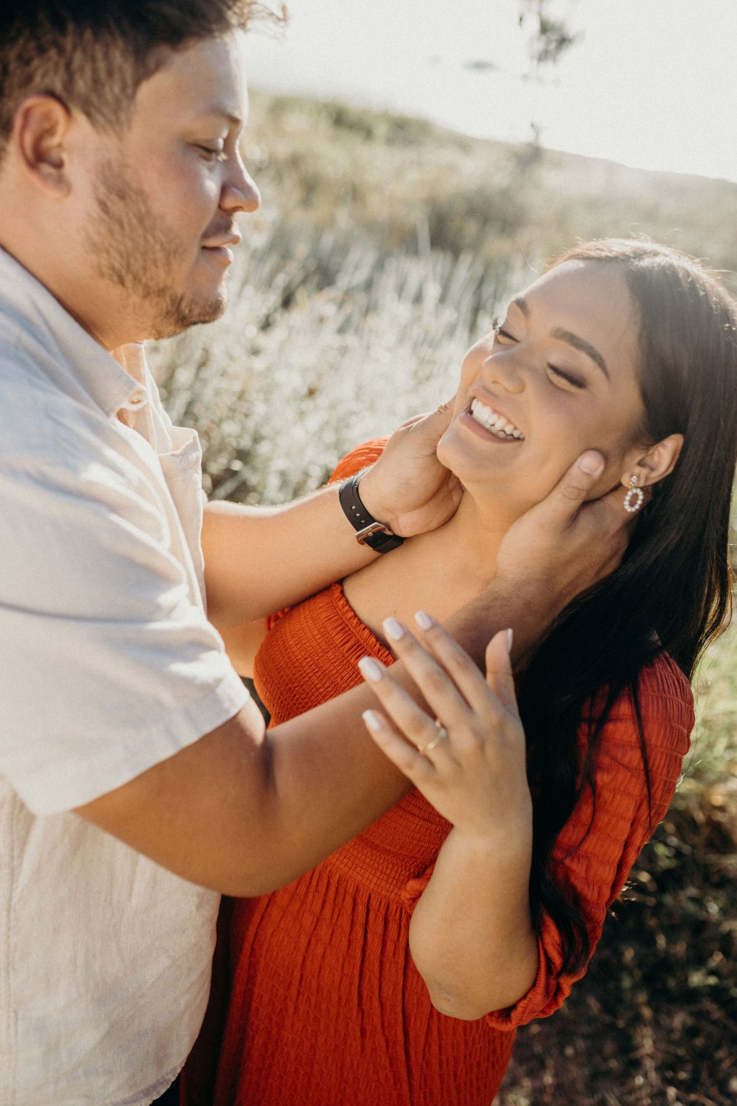 Joyful couple sharing intimate moment against mountain backdrop in warm sunlight.