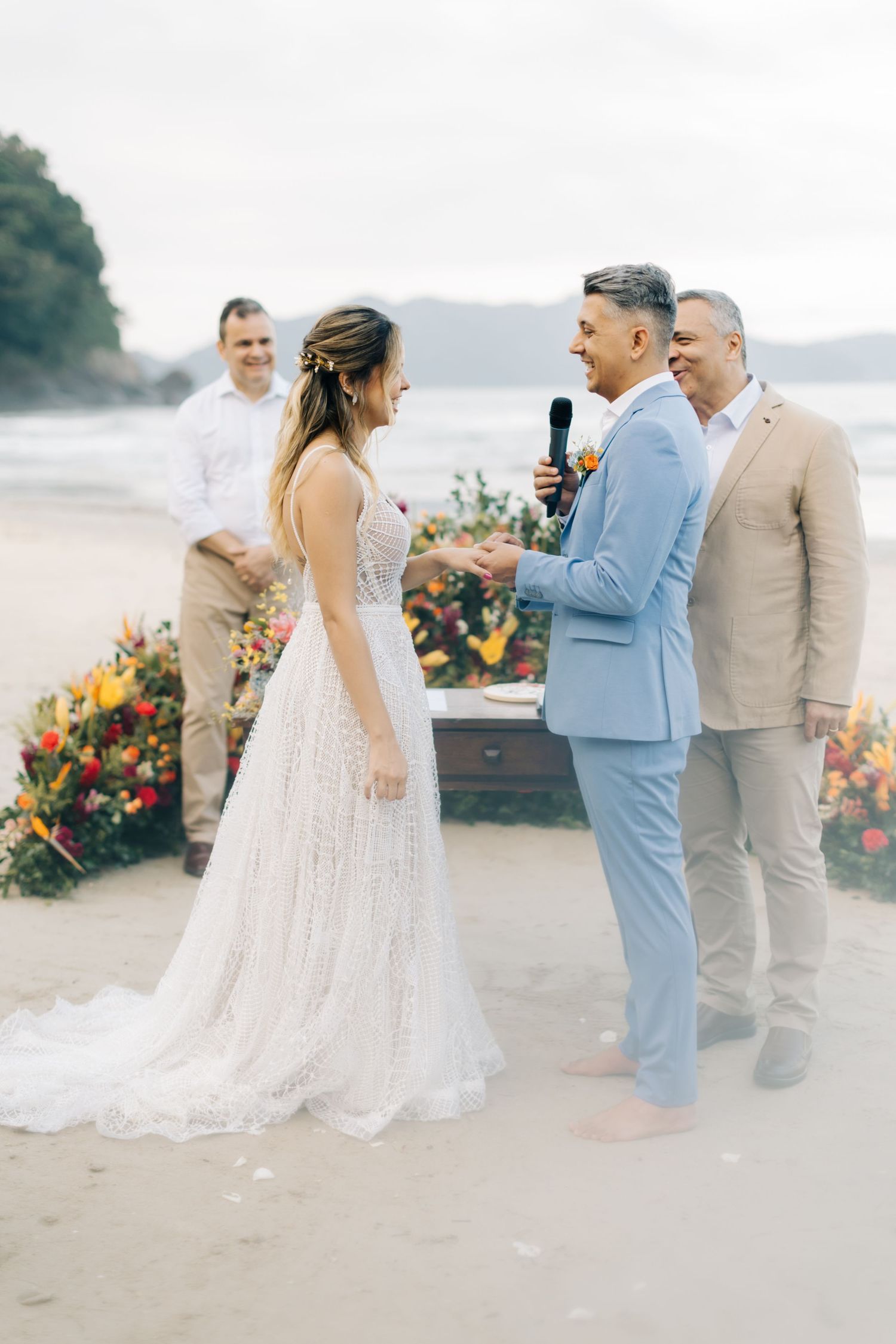 Intimate beach wedding ceremony with tropical floral decorations and guests gathered on the sand.