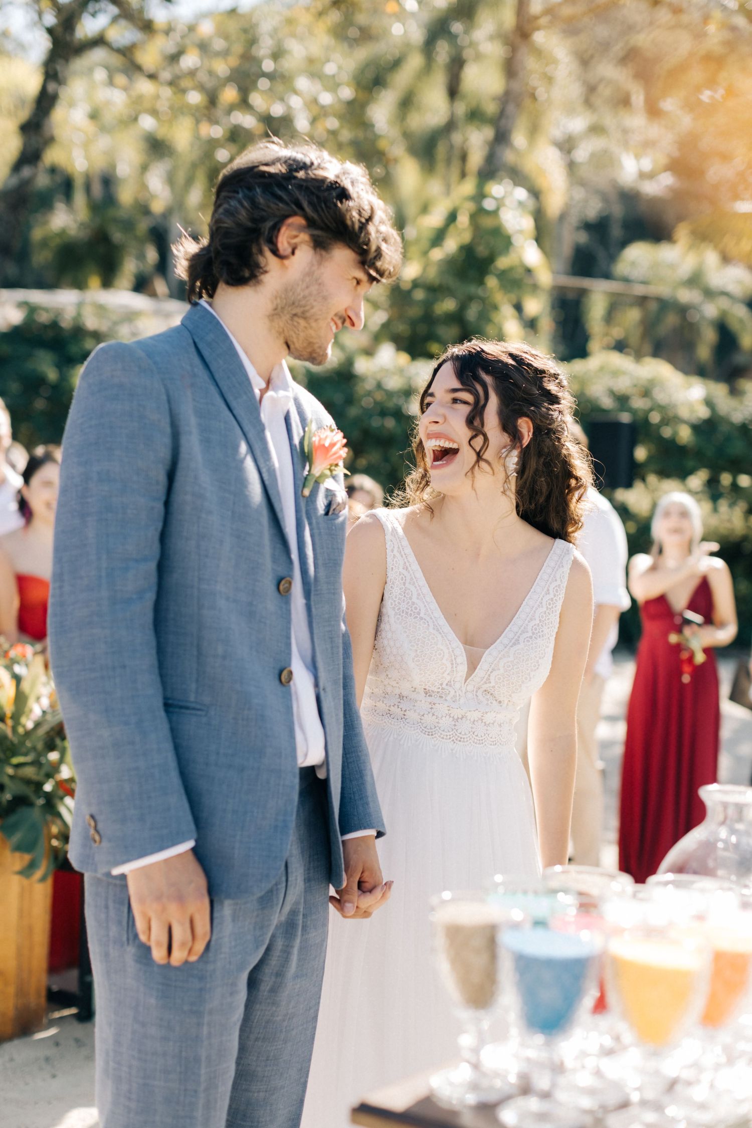 Couple sharing joyful moment at outdoor wedding with drinks display.