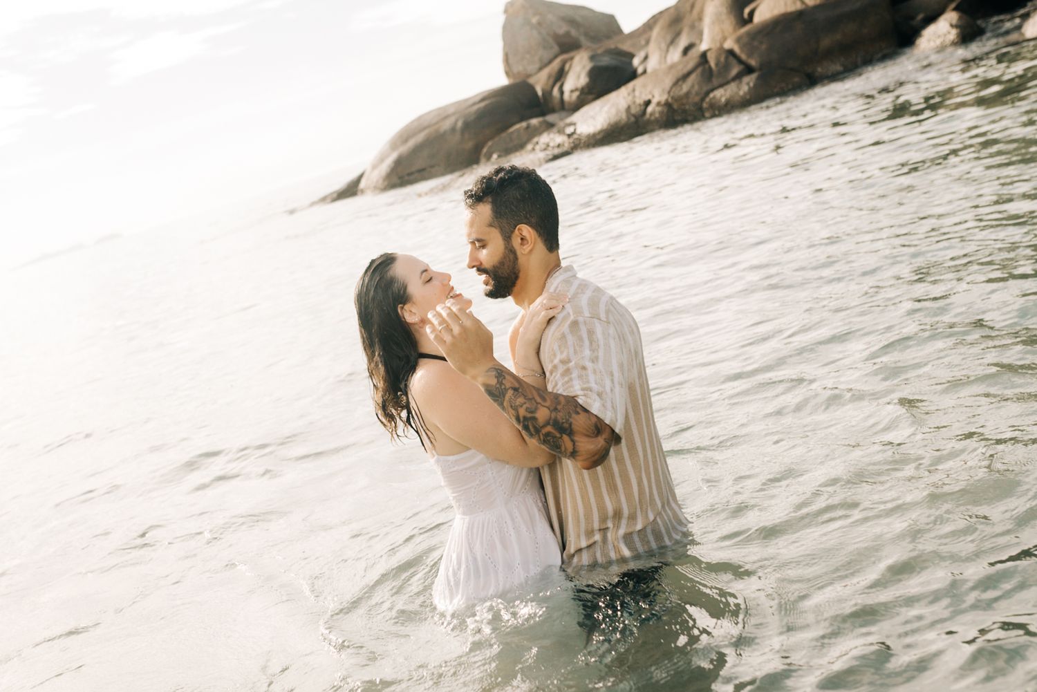 Two people share romantic moments in the ocean waves.