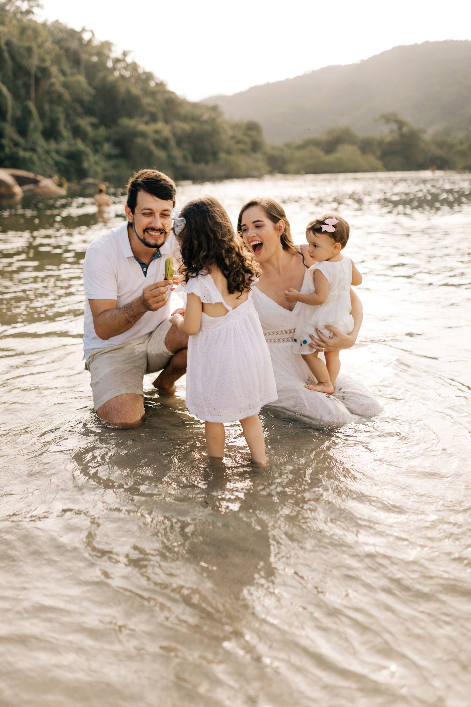 Family having fun and splashing in ocean water during sunset photoshoot.