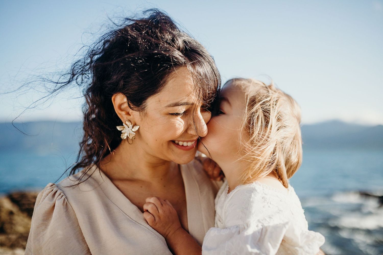 Intimate closeup of parent and child sharing sweet moment by the ocean.