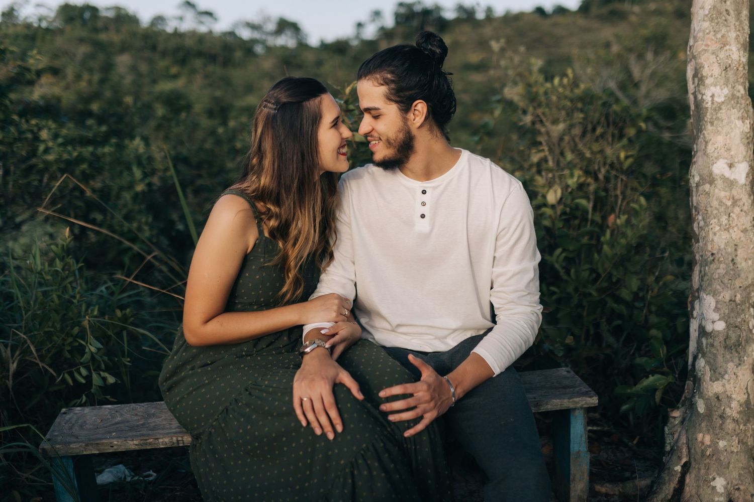 Intimate outdoor photoshoot with couple sitting on natural stone formation.