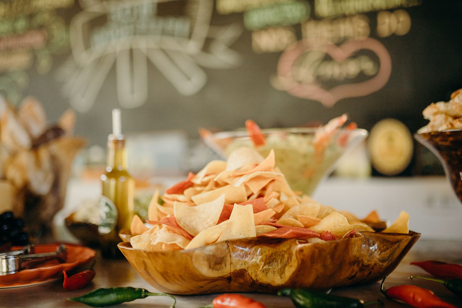 A plate filled with crispy tortilla chips served on a rustic wooden surface with garnishes.