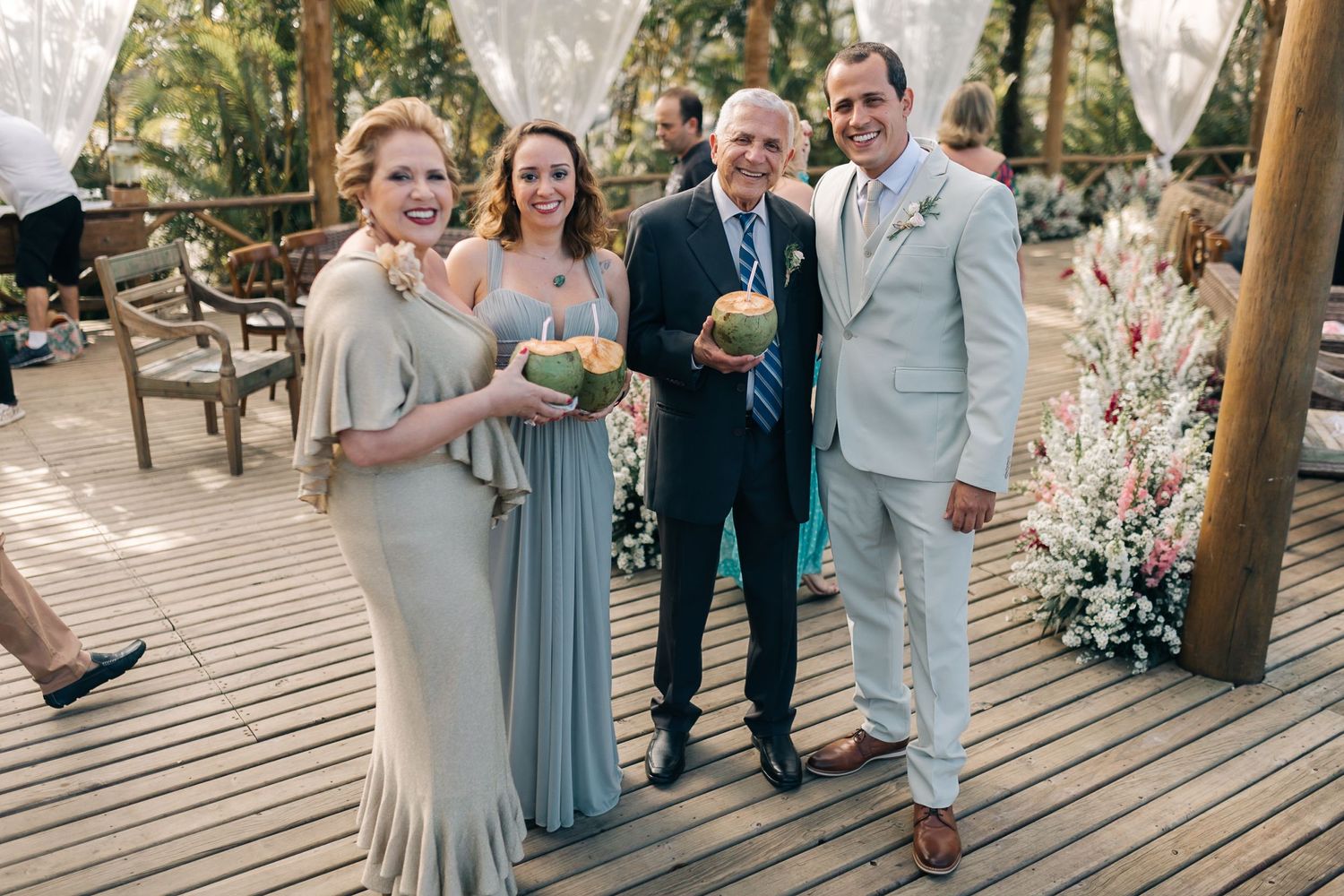 Wedding guests gather under a covered outdoor venue decorated with floral arrangements.