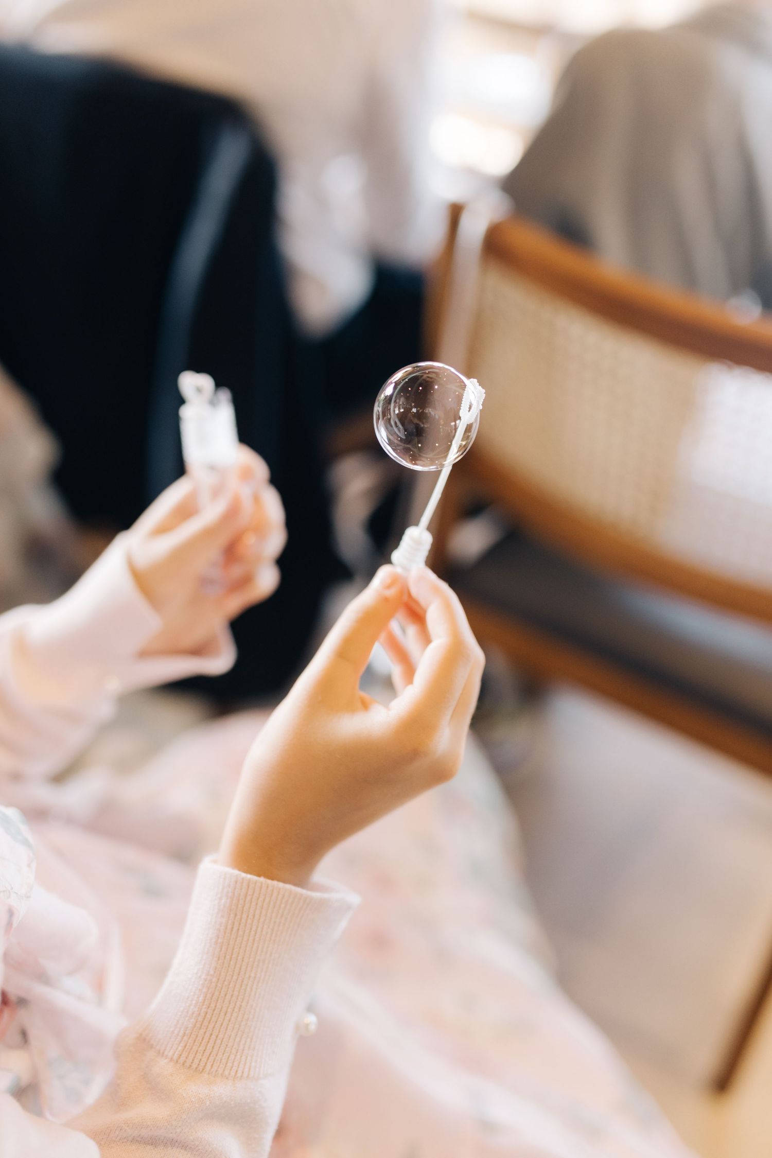 Close-up of hands holding a bubble wand at celebratory event.