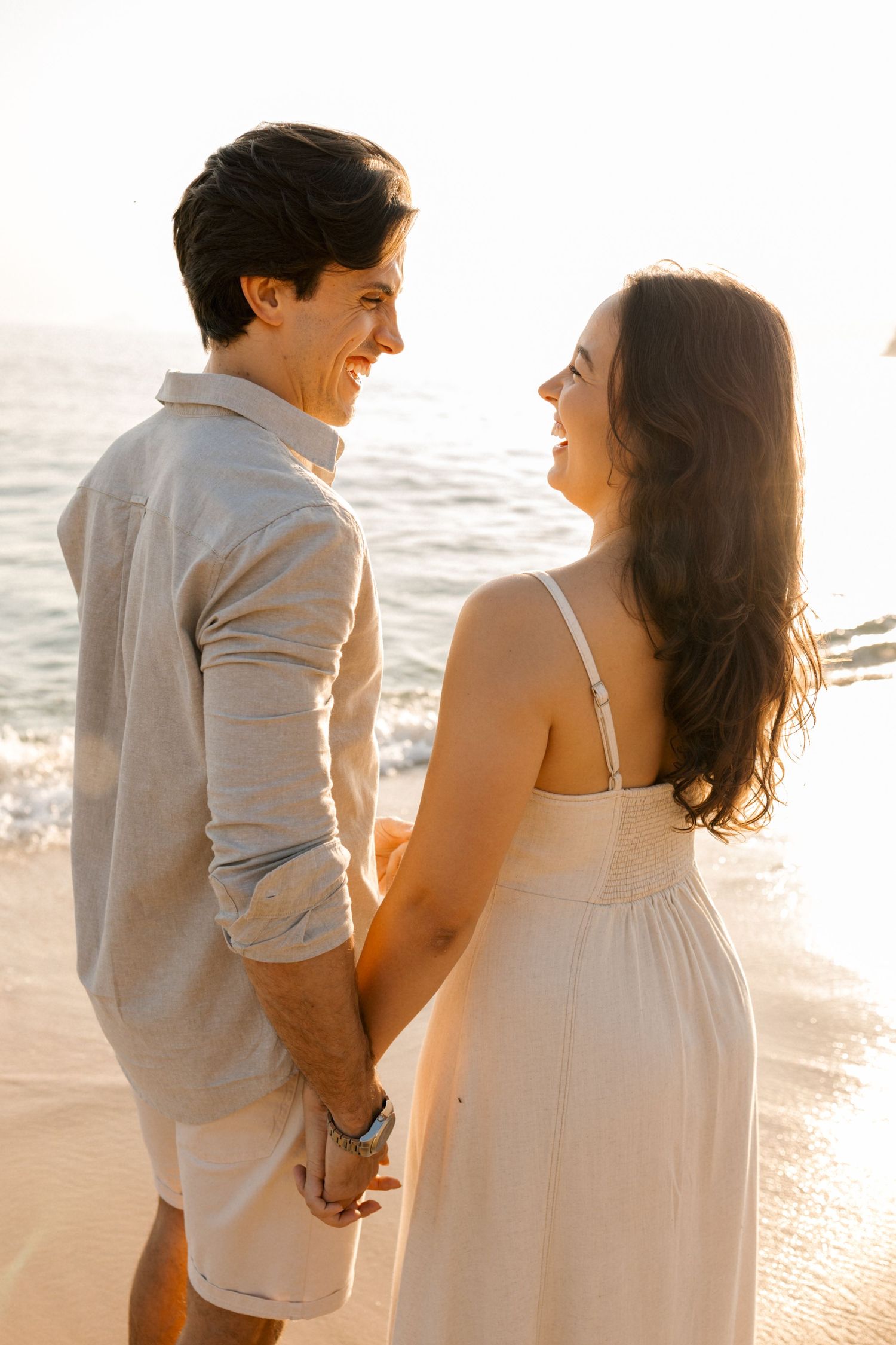 Couple shares joyful moments and laughter together on a sunlit beach.
