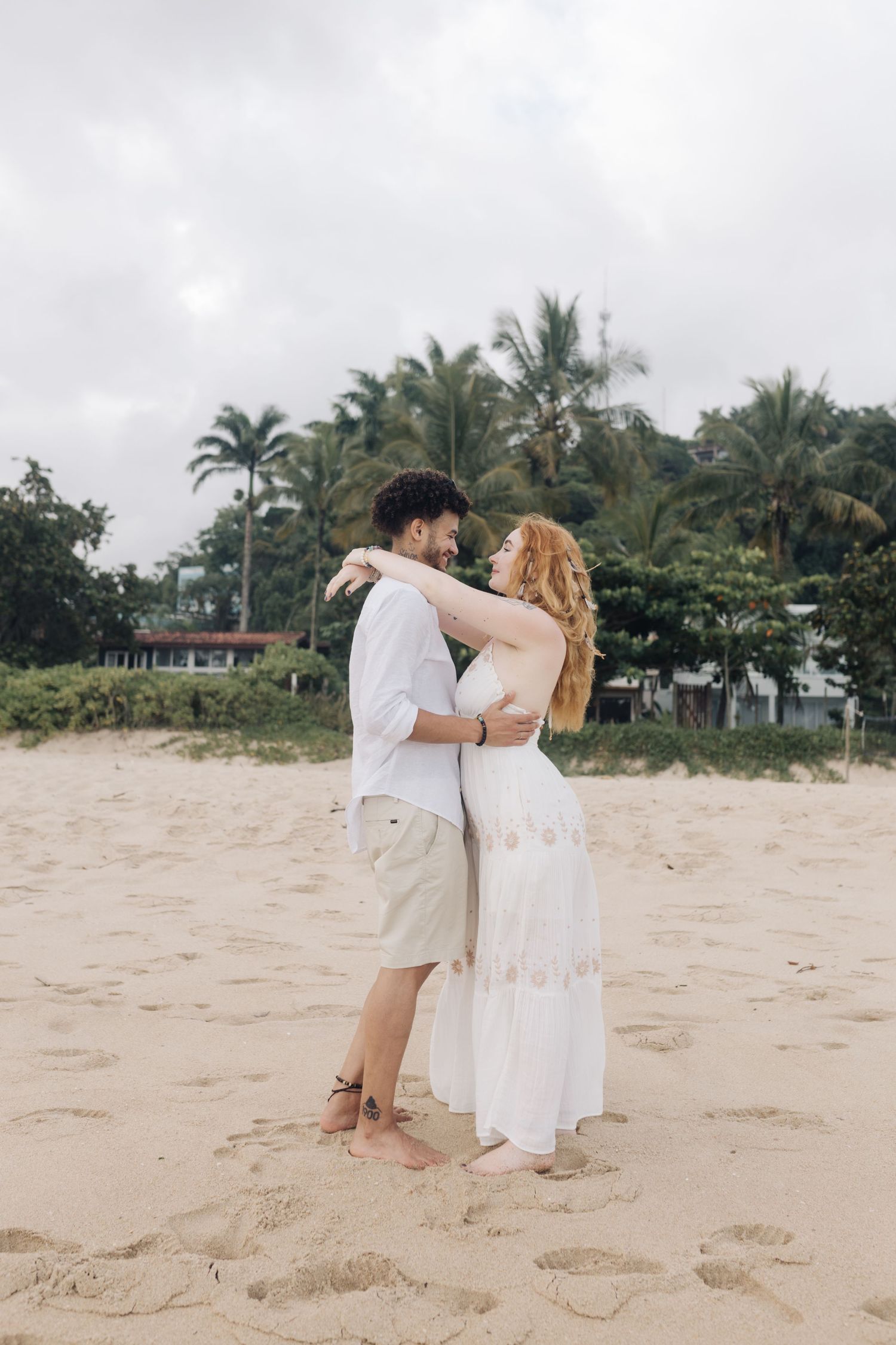A romantic embrace on a tropical beach with palm trees in the background.