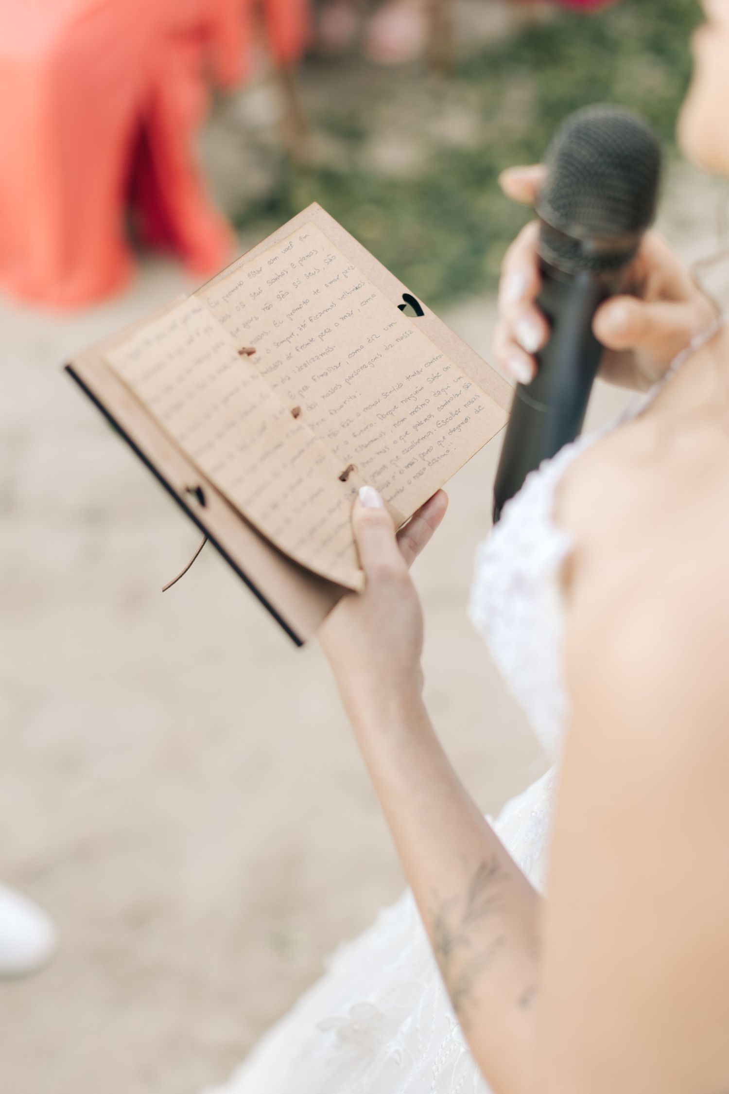 Close-up of wedding guest holding handwritten vows during beach ceremony.