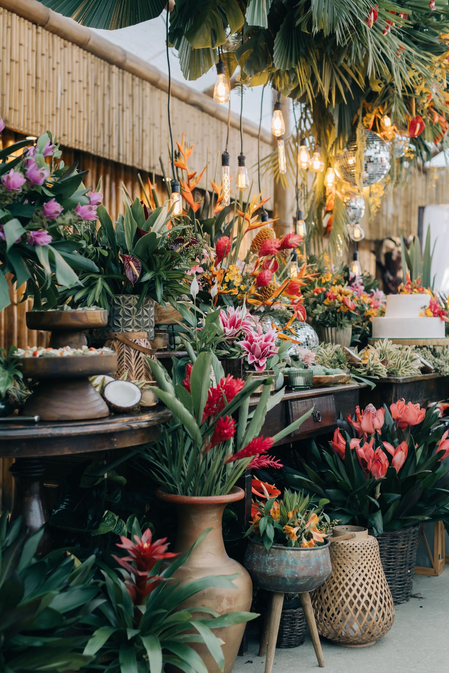 Tropical garden display with terracotta pots and woven baskets under bamboo ceiling.
