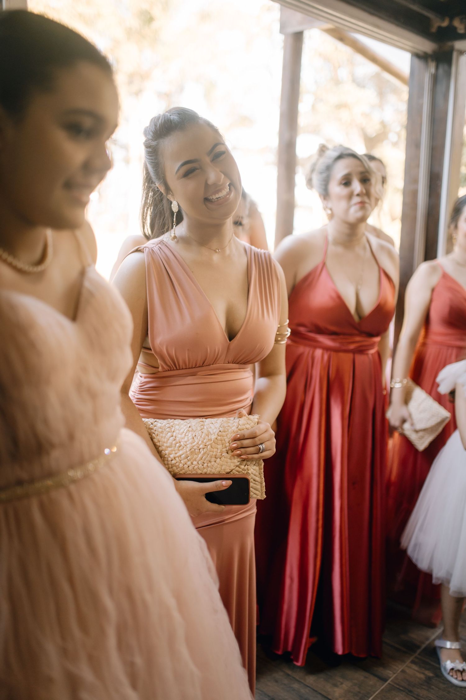 Wedding party members in coral and blush tones gather during celebration.