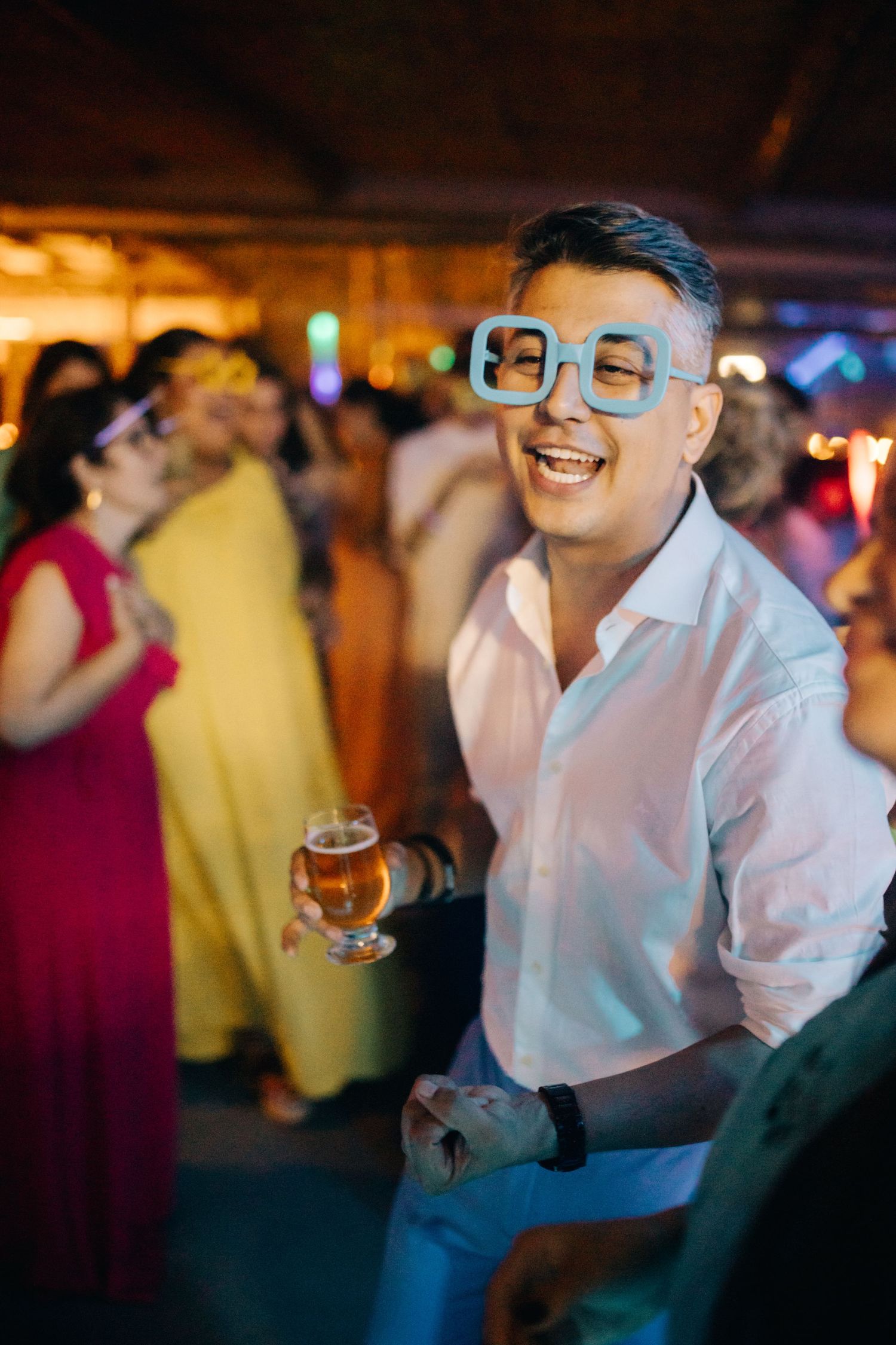 Guests enjoying drinks and dancing at a lively wedding reception party.
