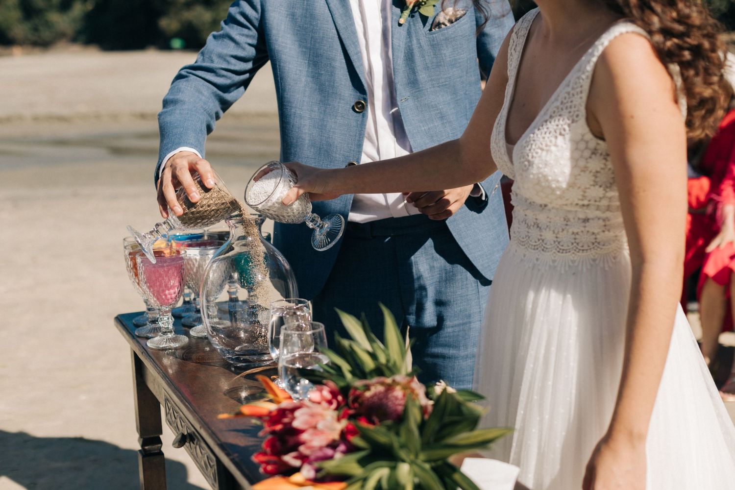Close-up of couple pouring drinks at elegant outdoor wedding beverage station.