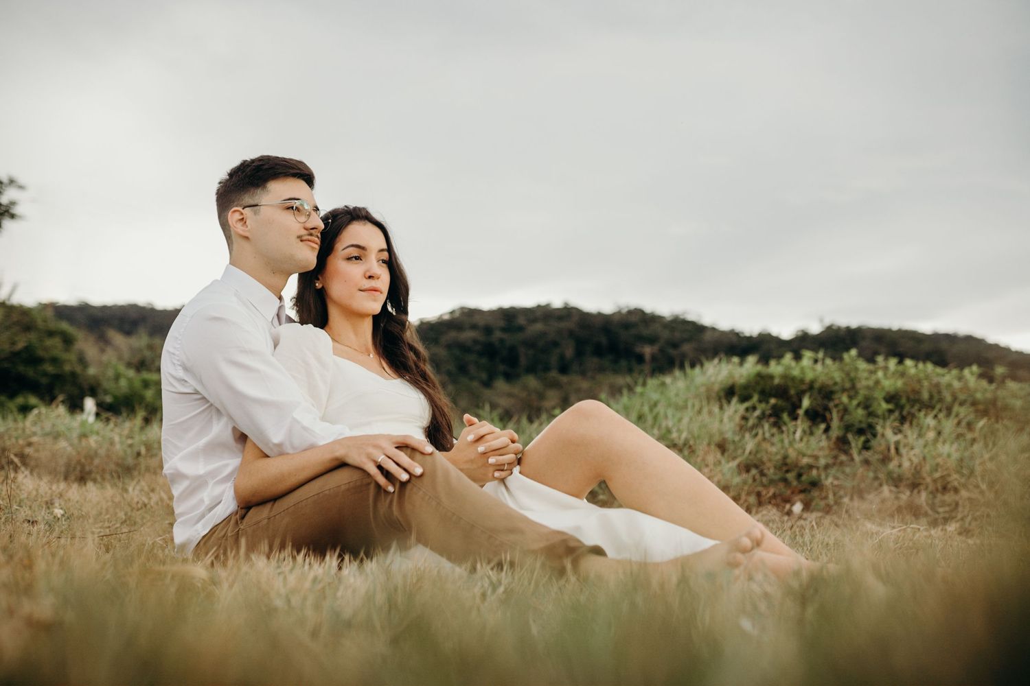 A couple relaxing together in a sunlit meadow with natural scenery.