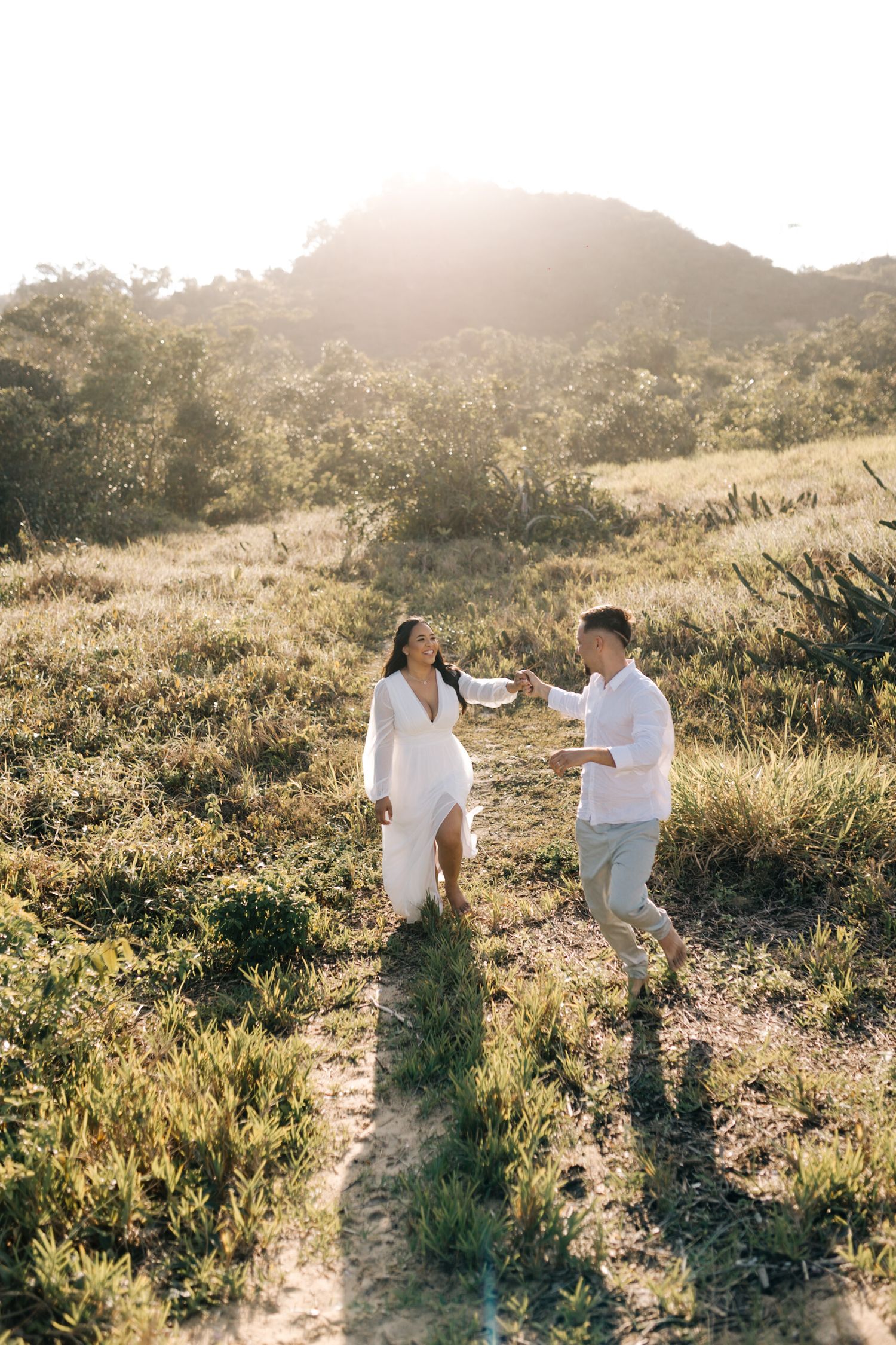 A couple shares a playful moment while walking along a scenic mountain path.