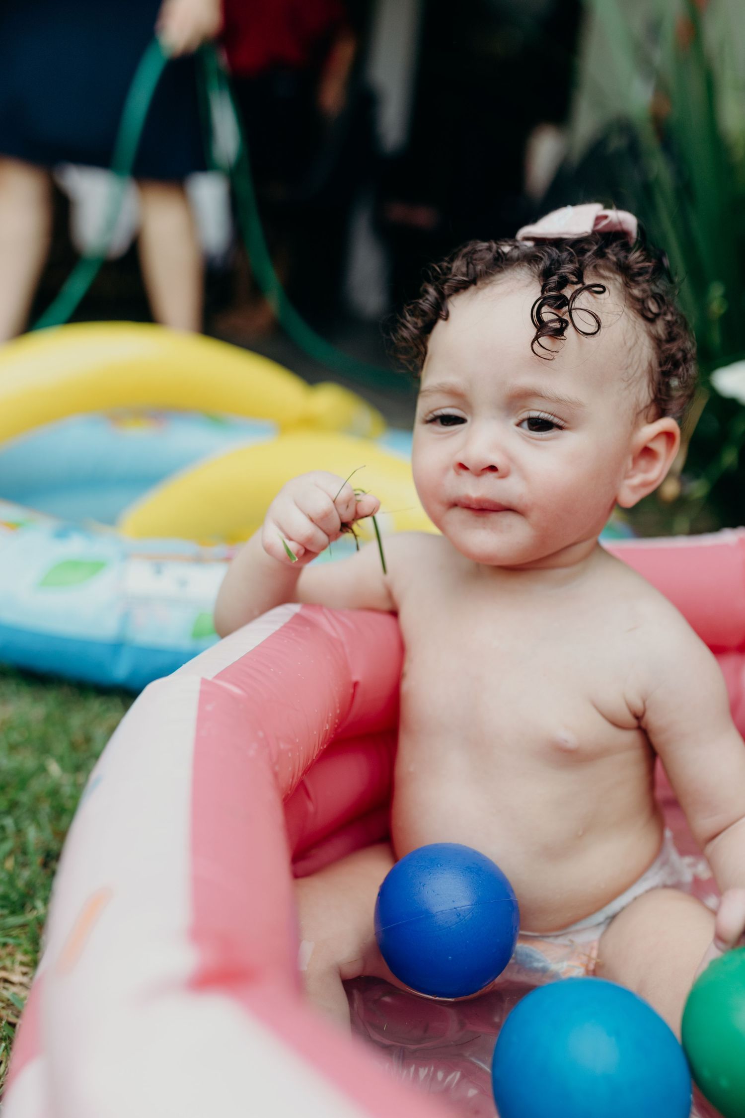Child playing in inflatable pool with bright colored balls.