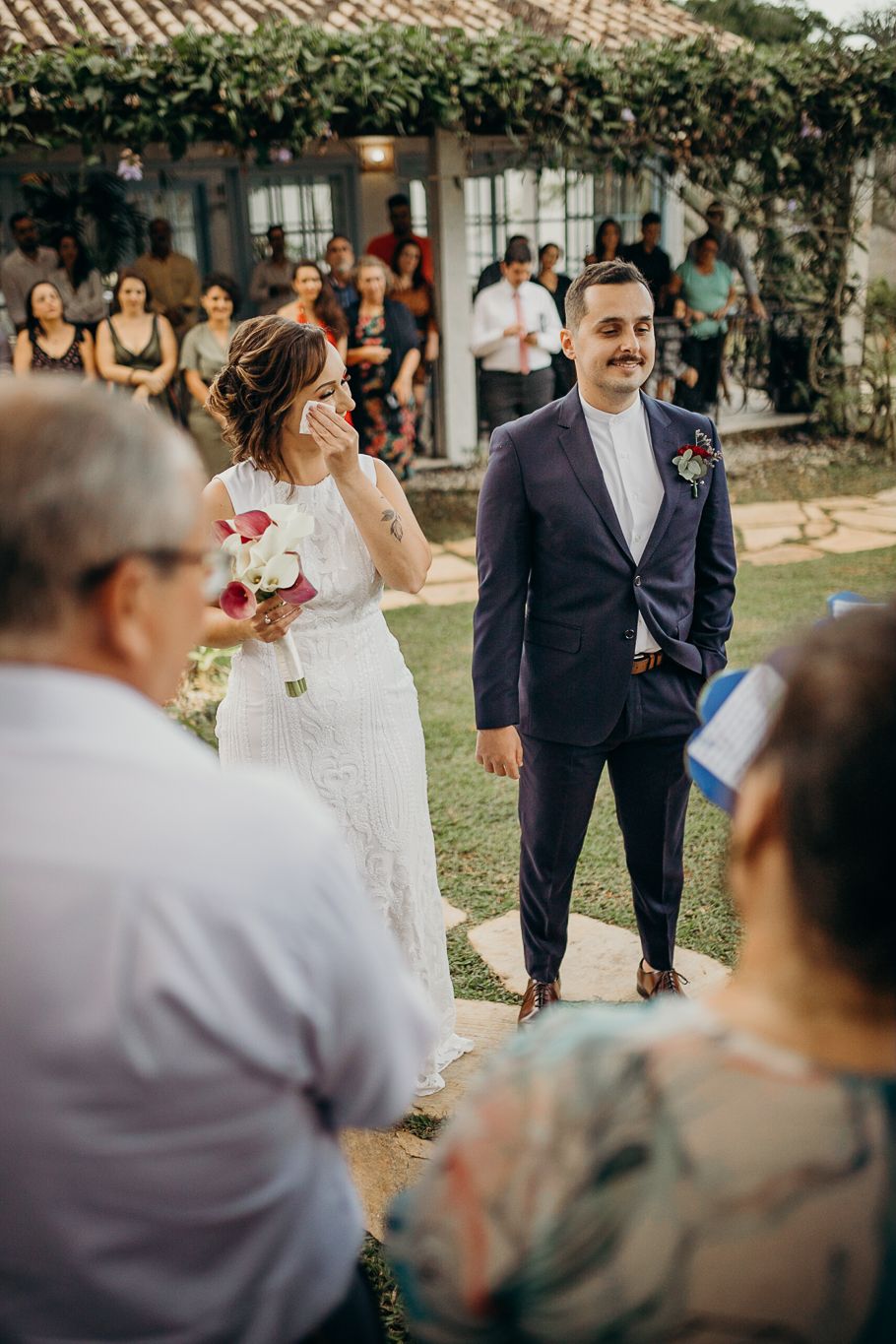 Wedding ceremony takes place on a stone pathway with guests watching from both sides.