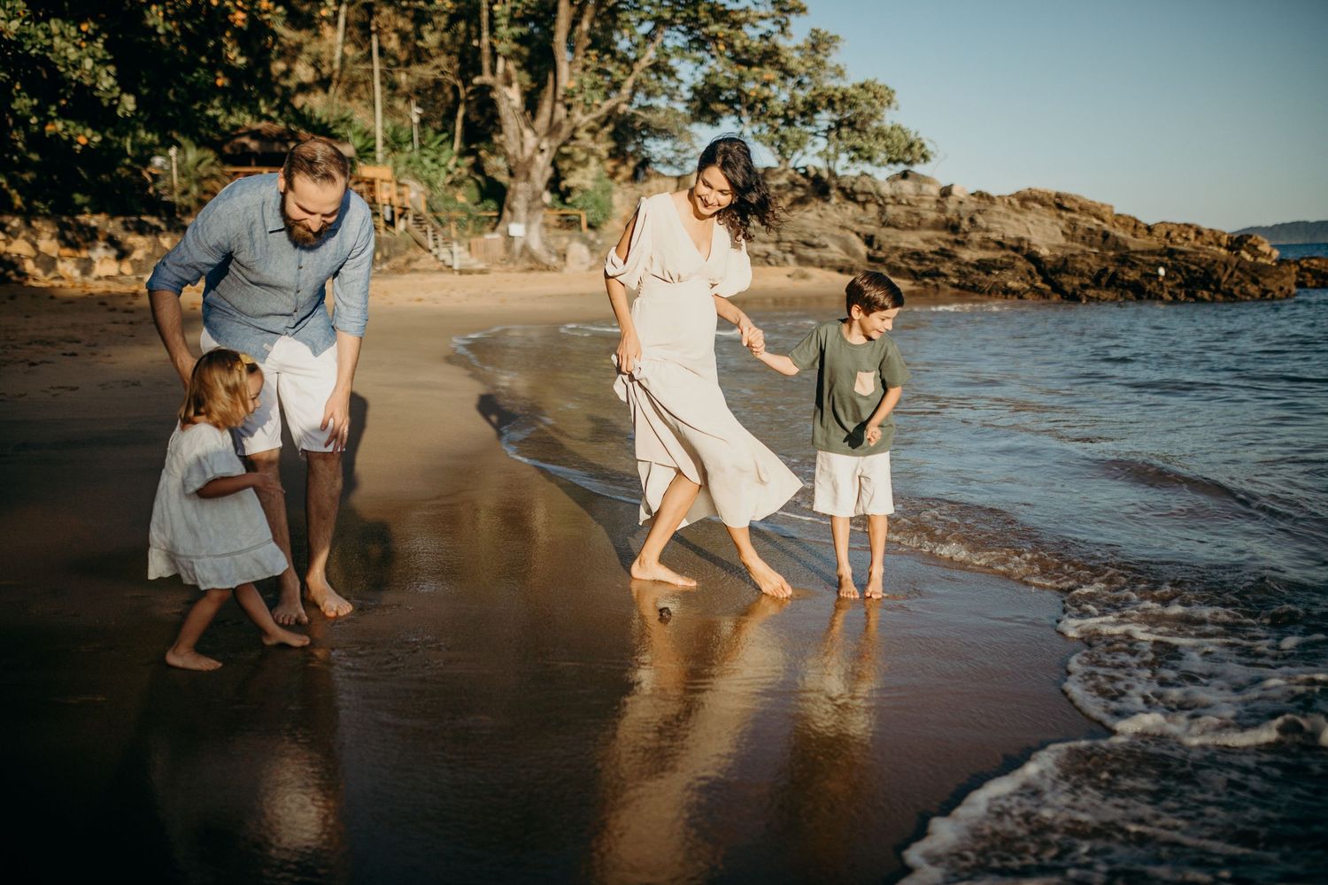 Candid moment of family playing in the wet sand at sunset on a tropical beach.