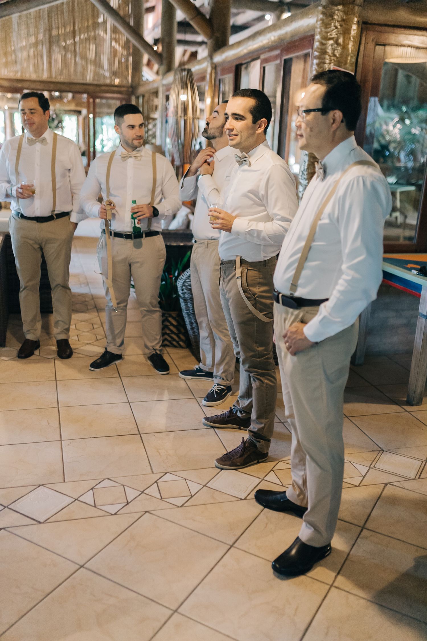 Group dressed in light colored formal attire playing a casual game indoors on tiled floor.