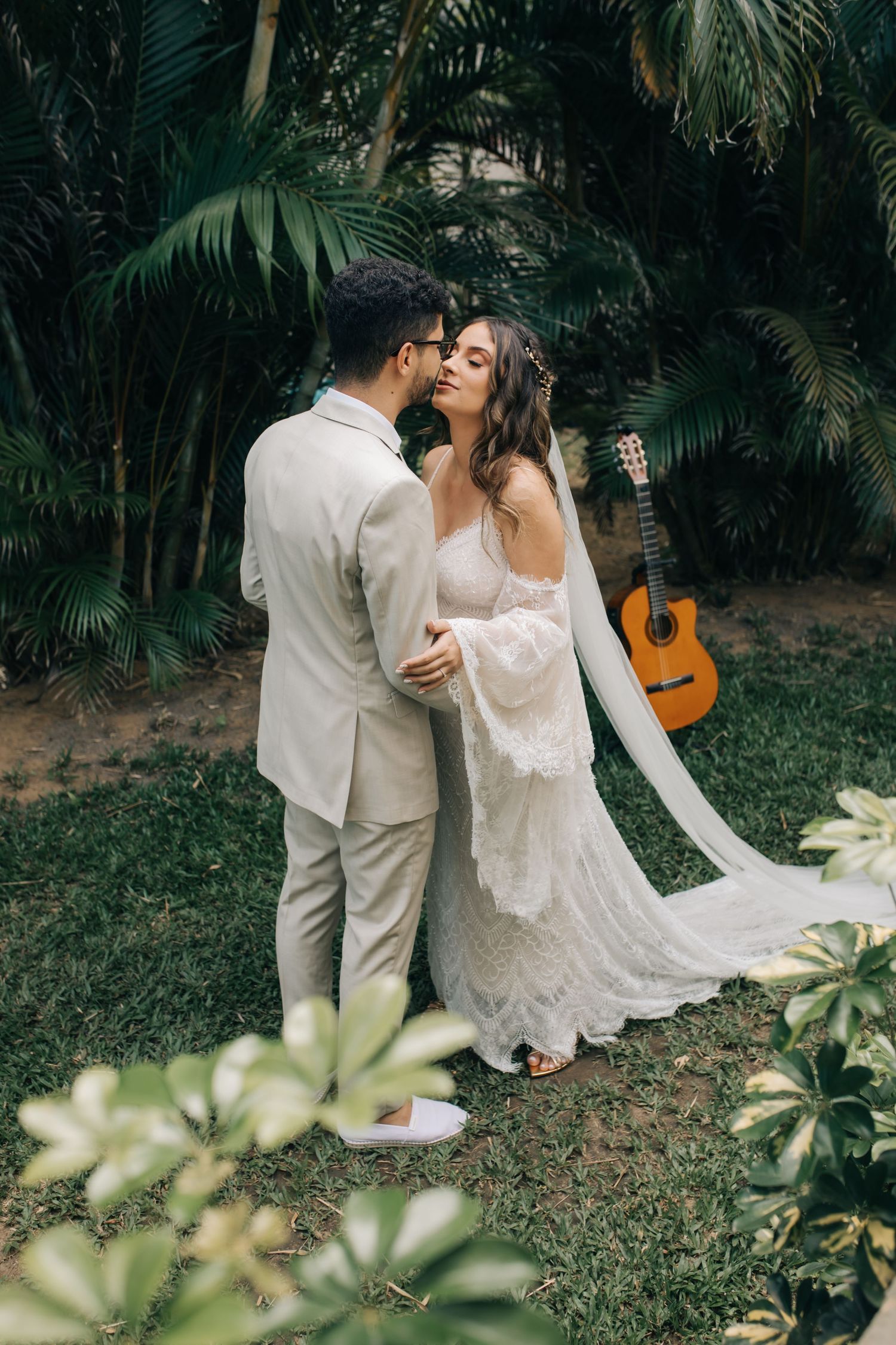 Intimate wedding moment in lush tropical garden setting with acoustic guitar in background.