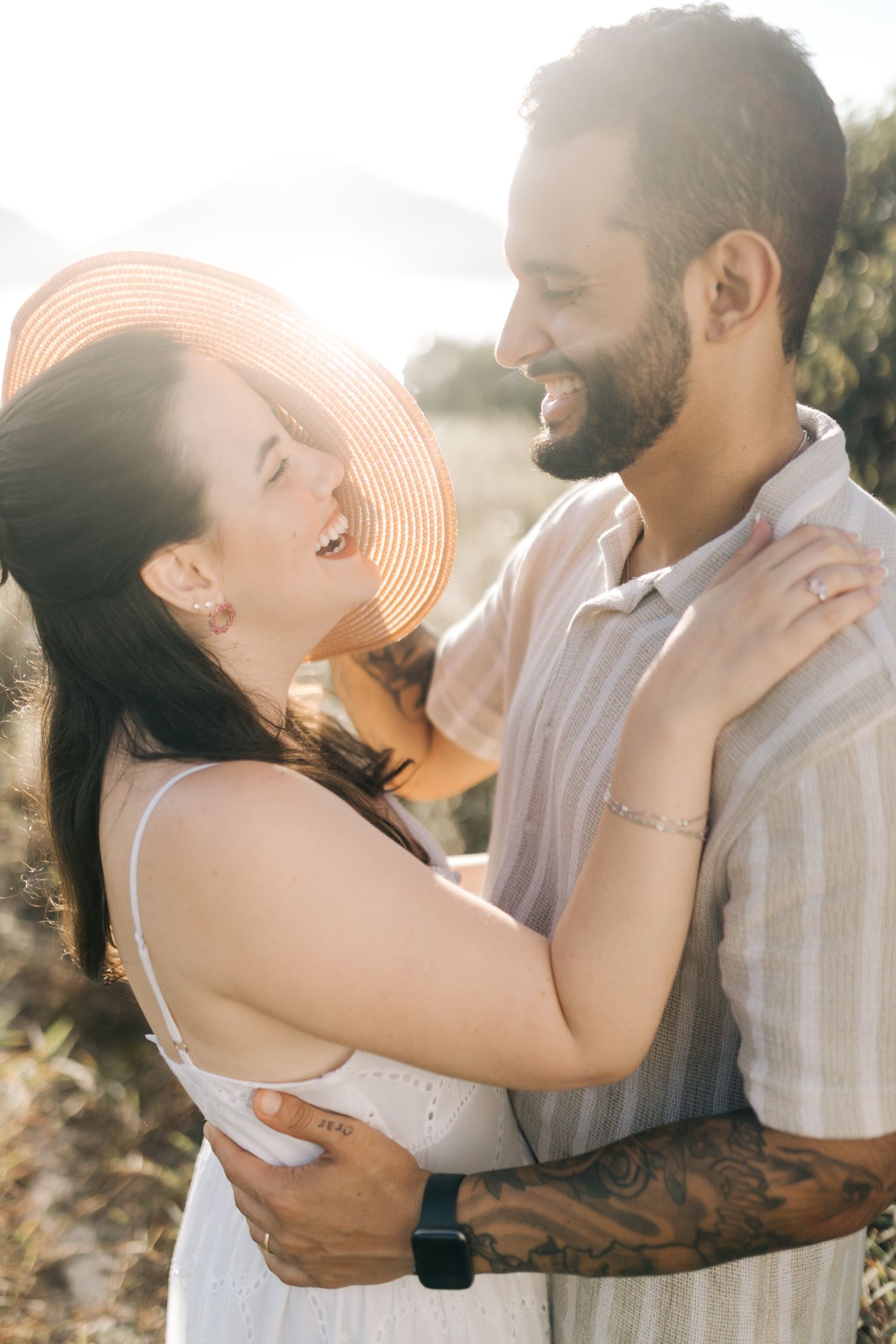 Couple sharing joyful embraces and laughter in sunset lighting outdoors.