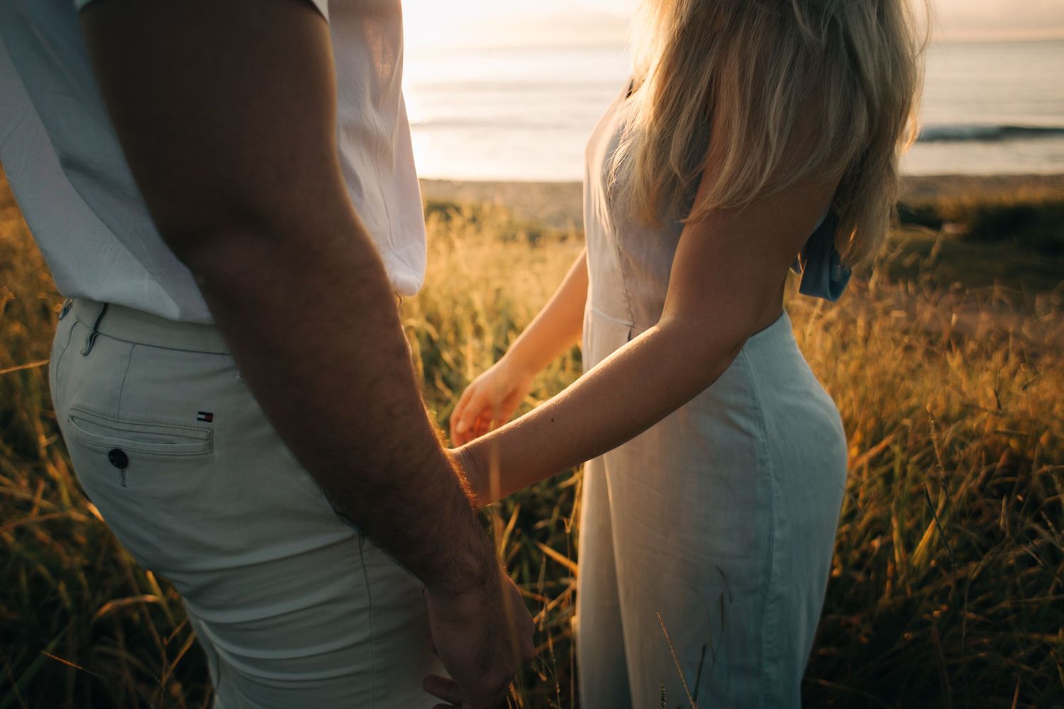 Side view of couple in white clothing sharing romantic moment by the ocean.