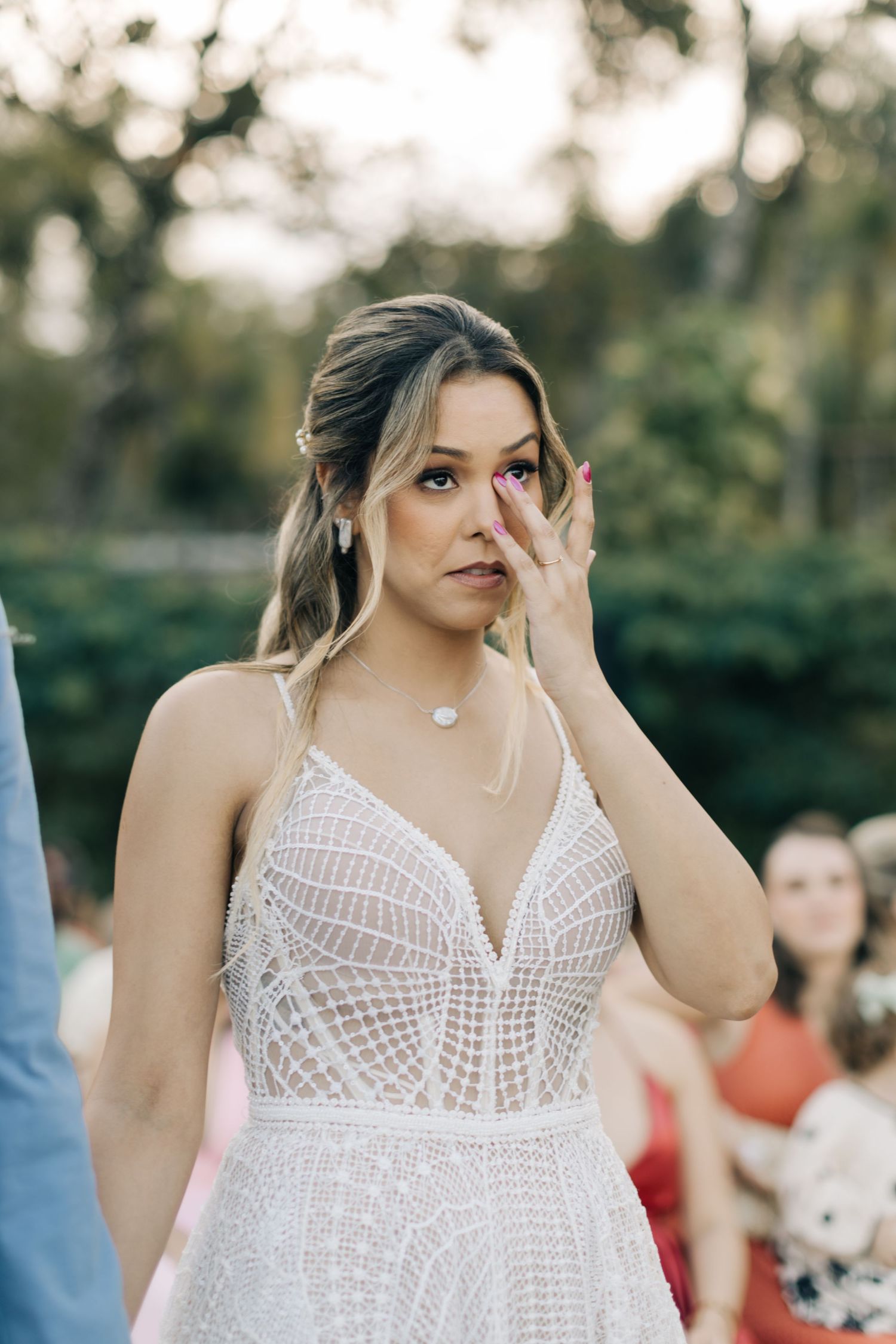 Emotional moment during outdoor wedding with garden backdrop.