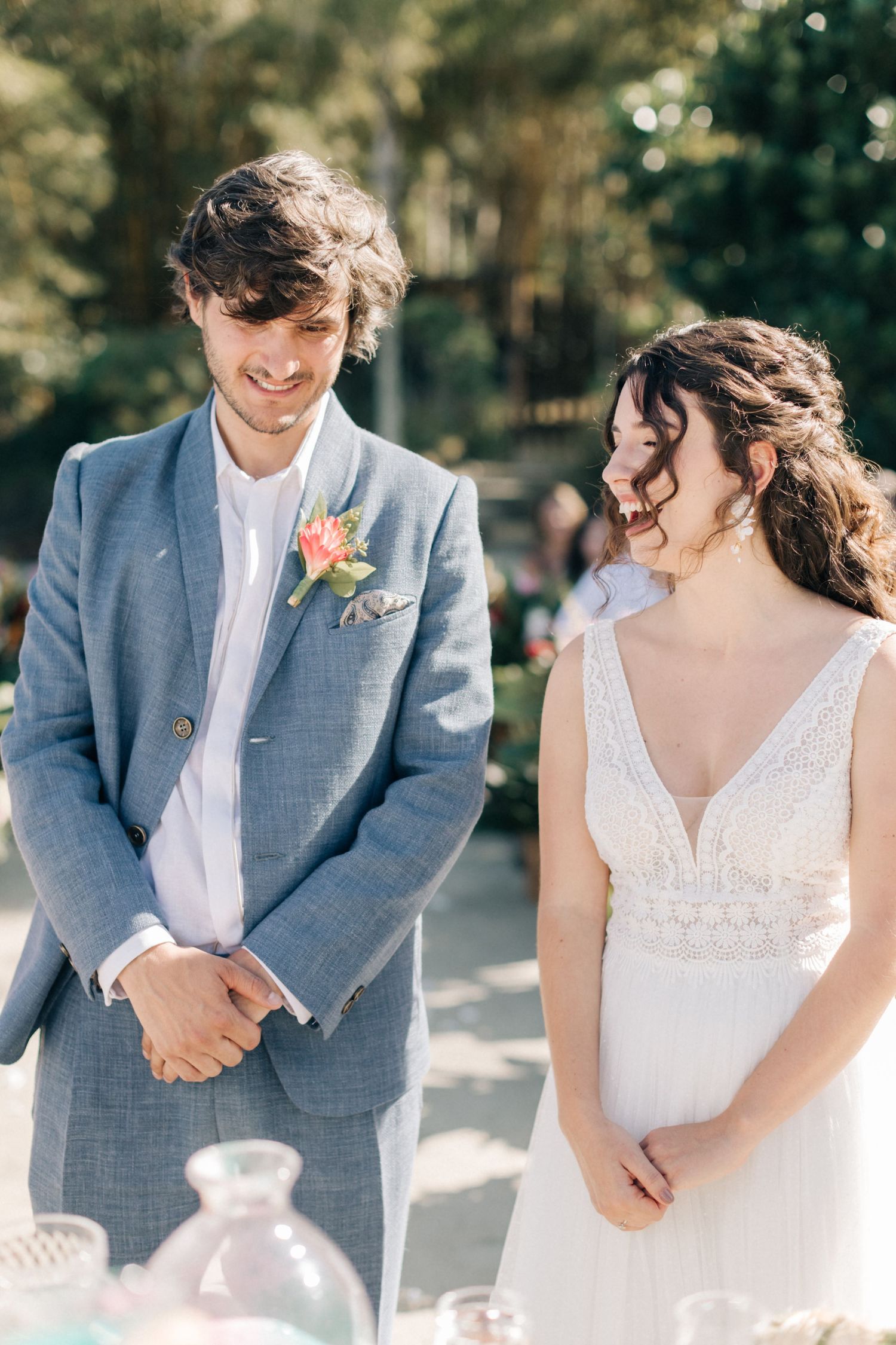 Couple shares joyful moment during outdoor wedding ceremony next to beverage display.