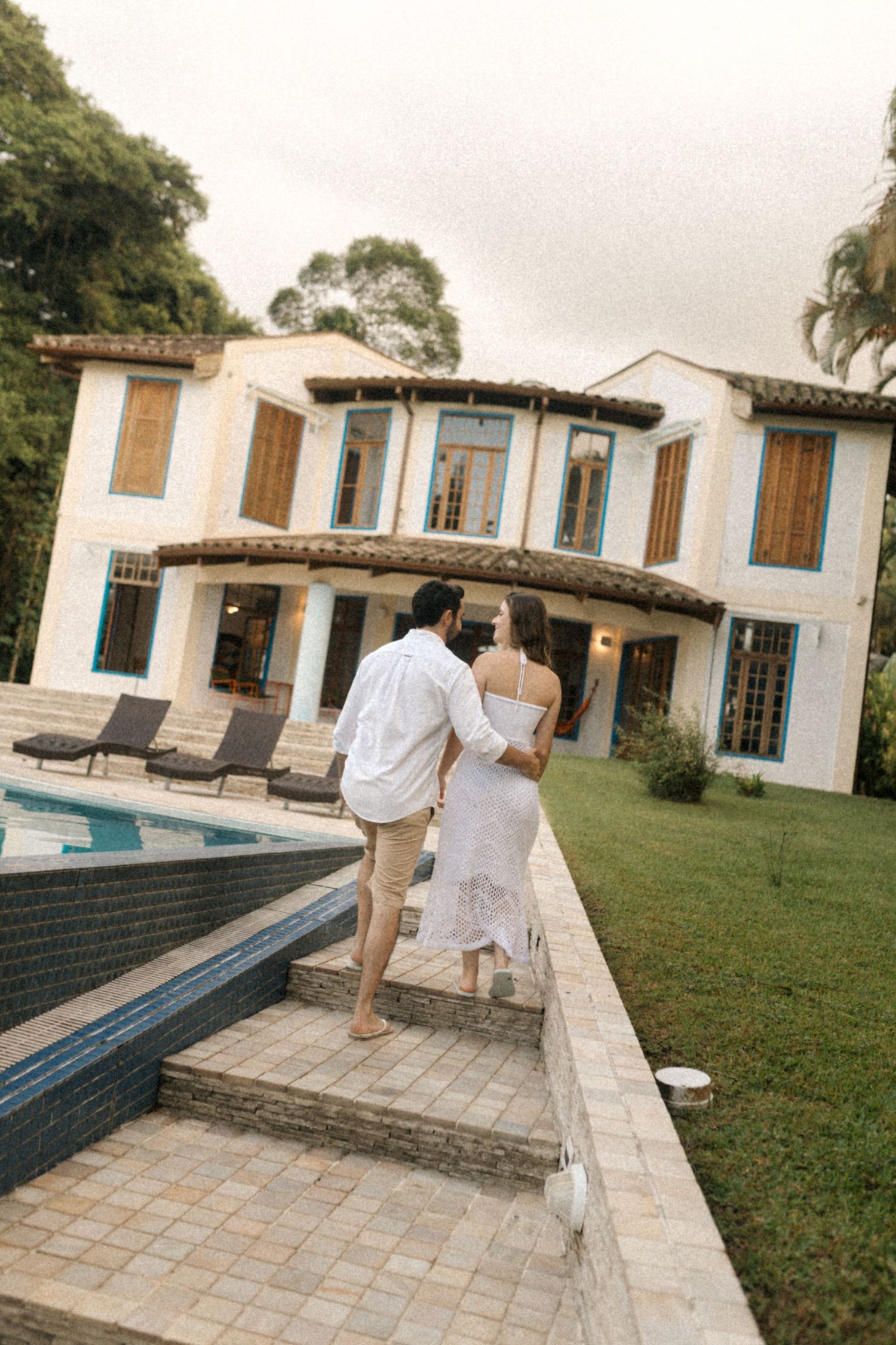 Couple walking along the edge of an infinity pool at an elegant Mediterranean-style villa.