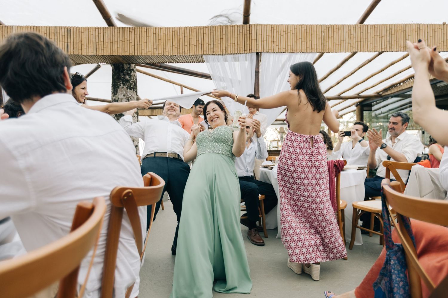 Guests having fun dancing and playing games at wedding reception under covered venue.