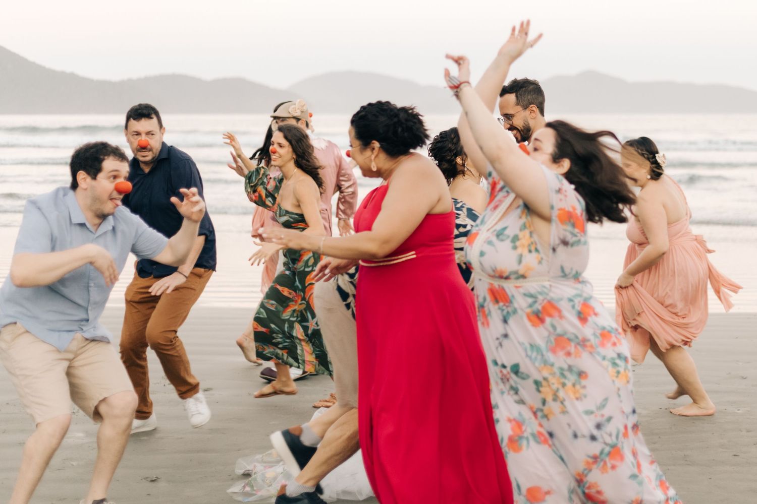 Wedding guests dancing and celebrating joyfully on the beach at sunset.