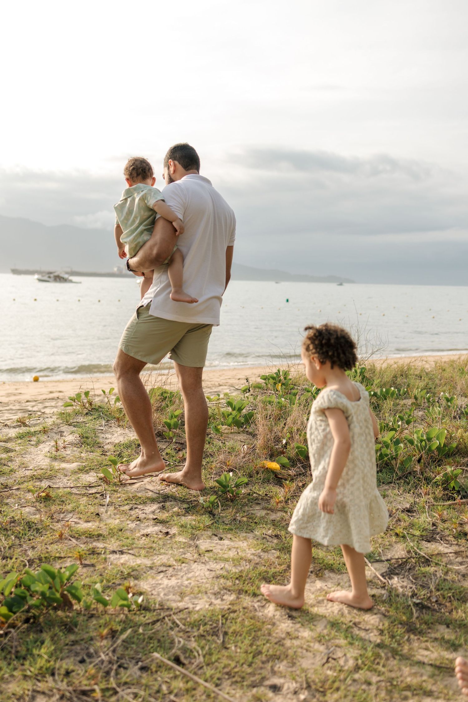 Family walking along a scenic beach shoreline during golden hour.