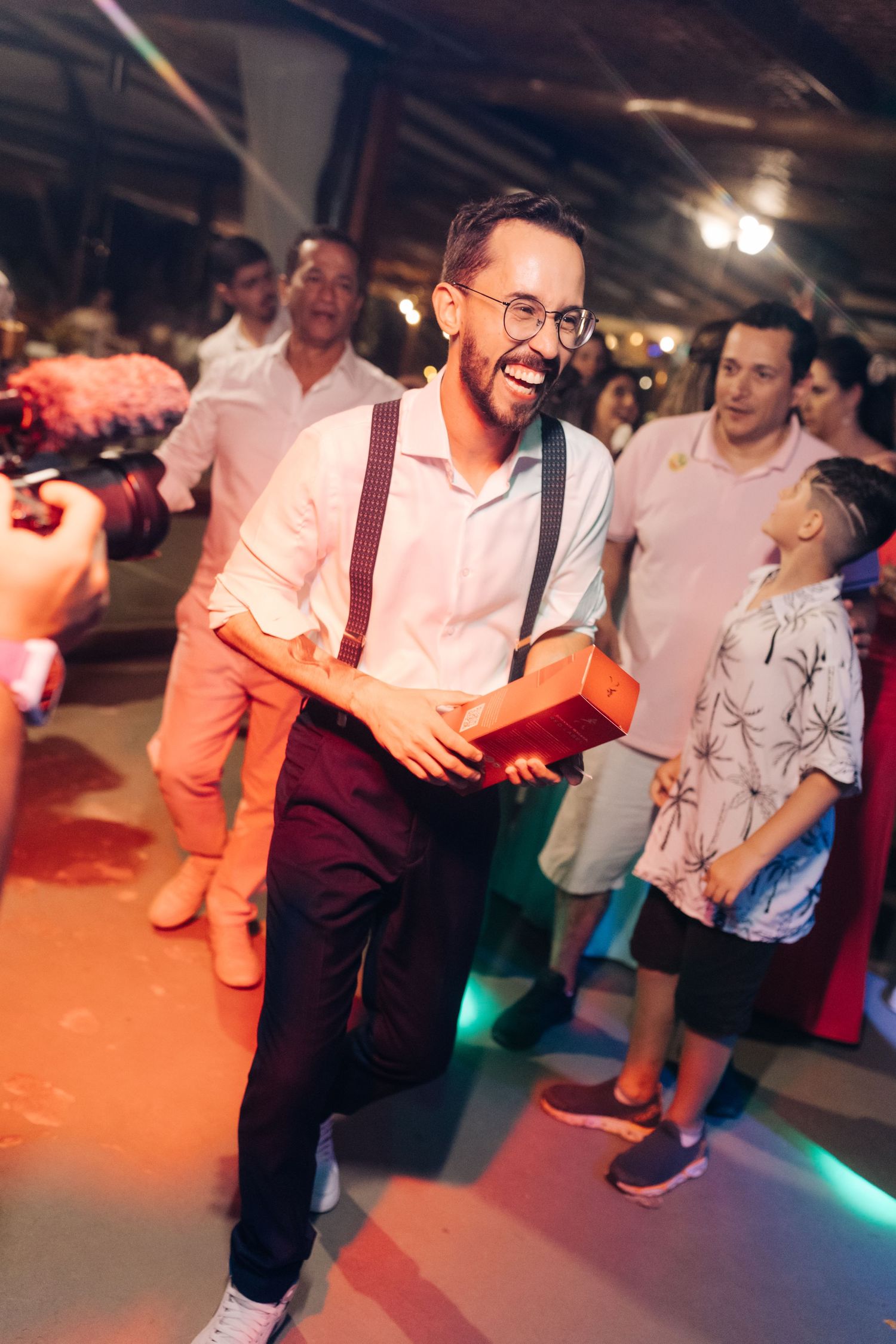 Wedding guest dancing and laughing at indoor reception party.
