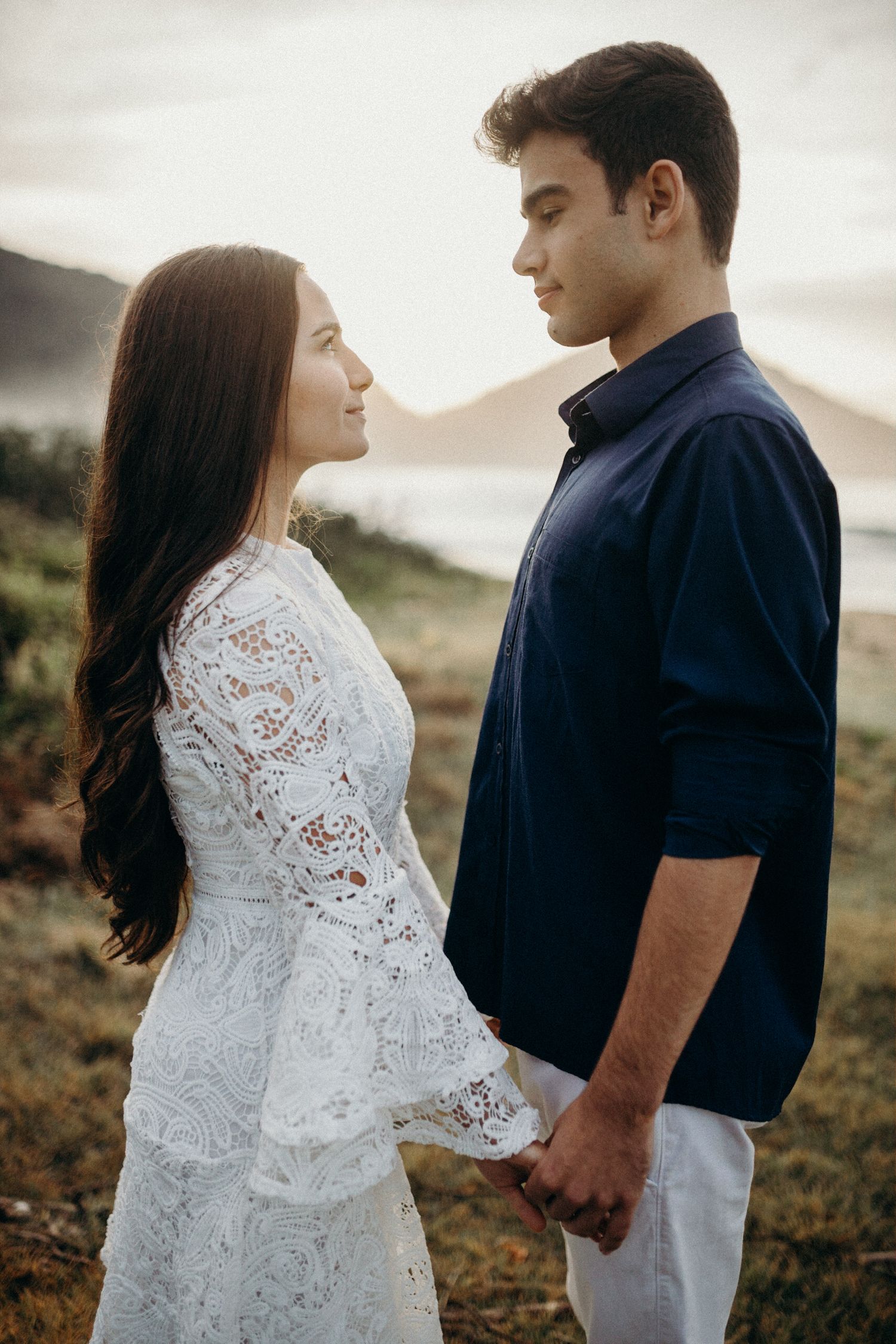 Intimate outdoor portrait session featuring a white lace dress and navy shirt against mountains.