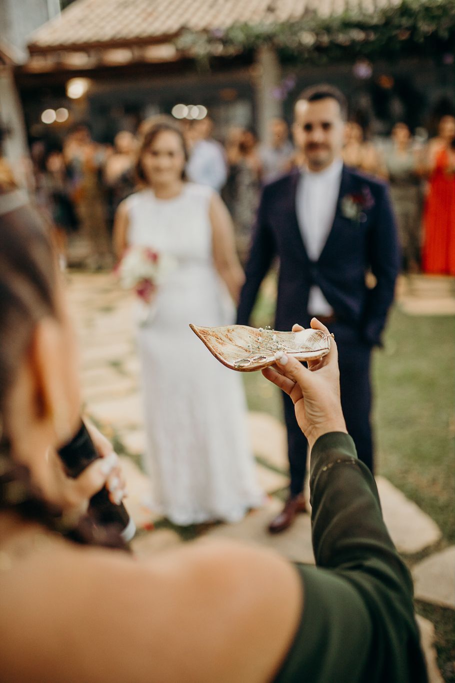 Wedding ceremony guest holds up a decorative item against the backdrop of the celebration.
