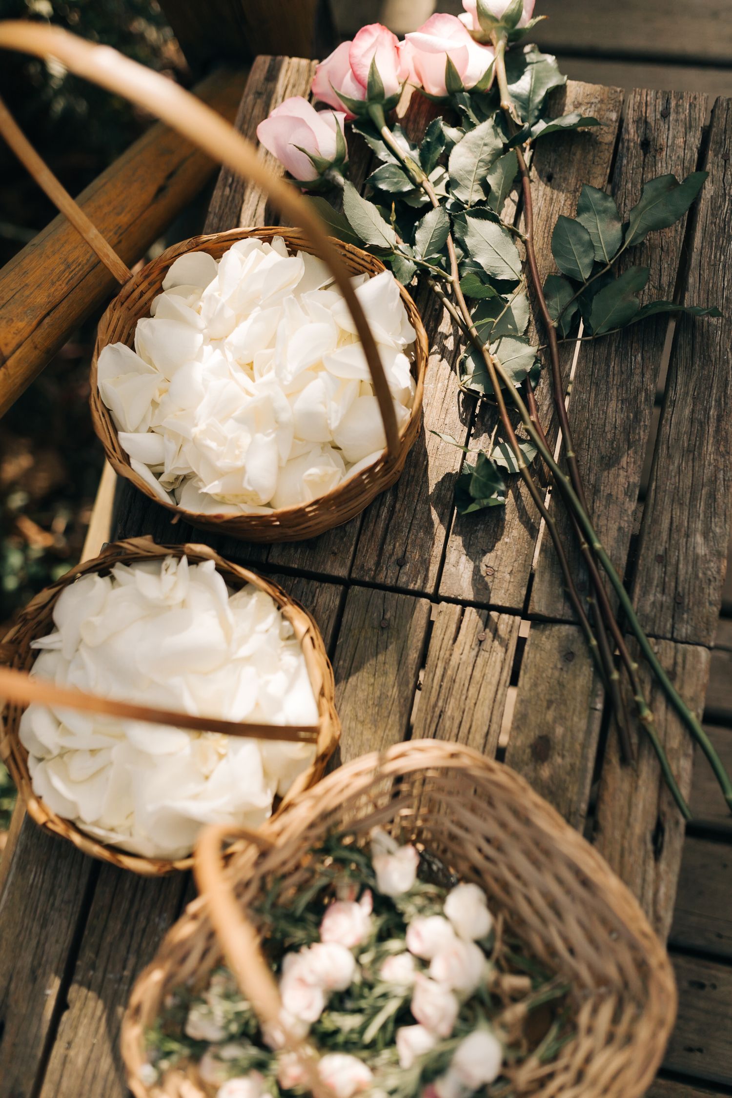 Rustic wooden table with white flower petals and decorative baskets.