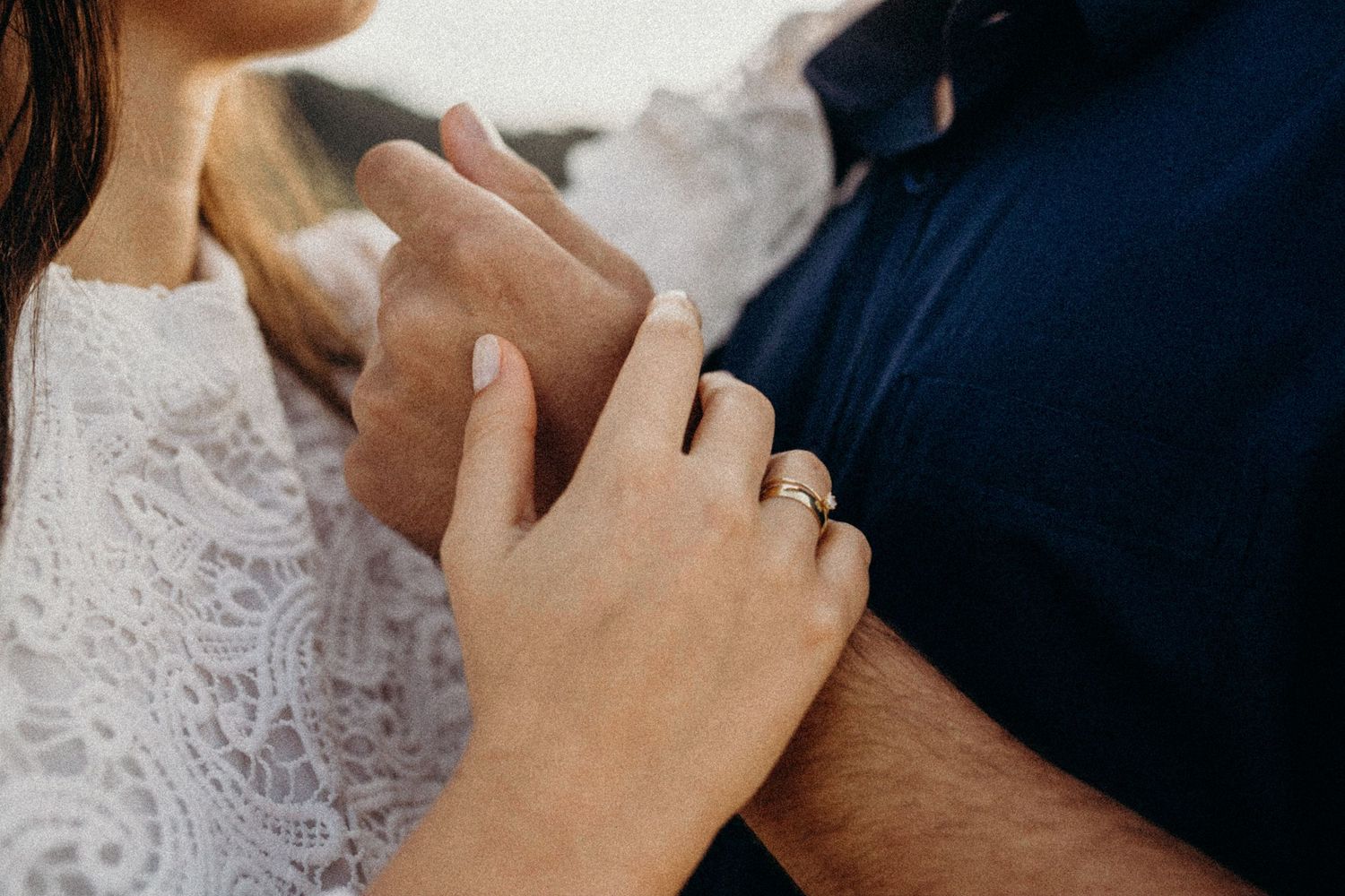 A close-up detail shot showing hands wearing white lace and navy blue clothing.