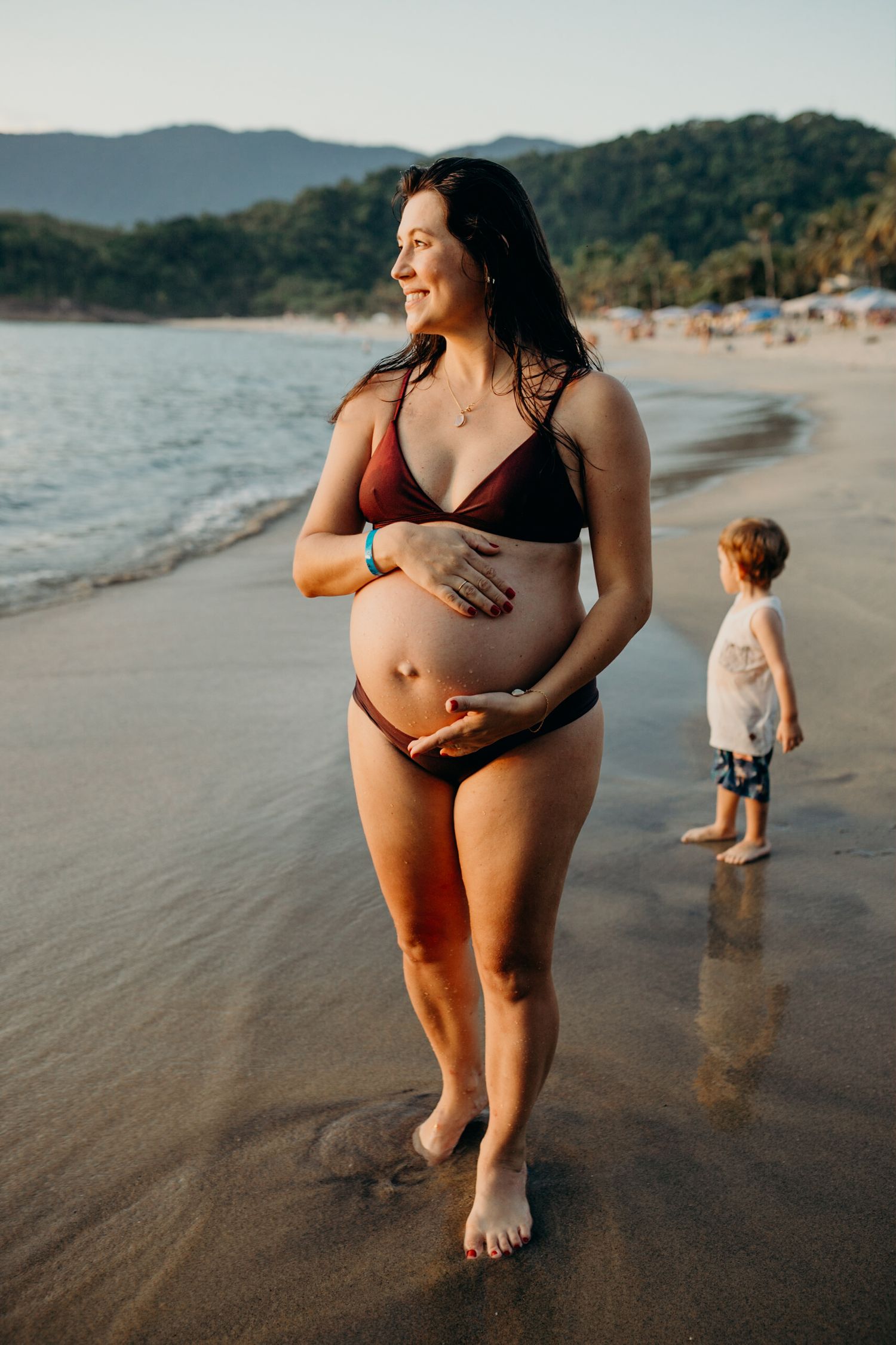 Family enjoying time at a scenic beach with mountains and waves in the background.