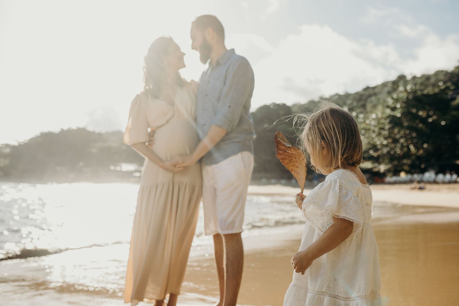Family maternity photo session at sunset on a sandy beach.